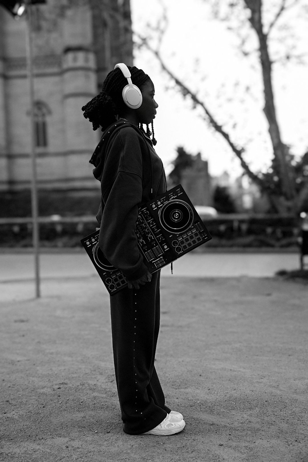 Black and white photo of female DJ with controller outdoors.