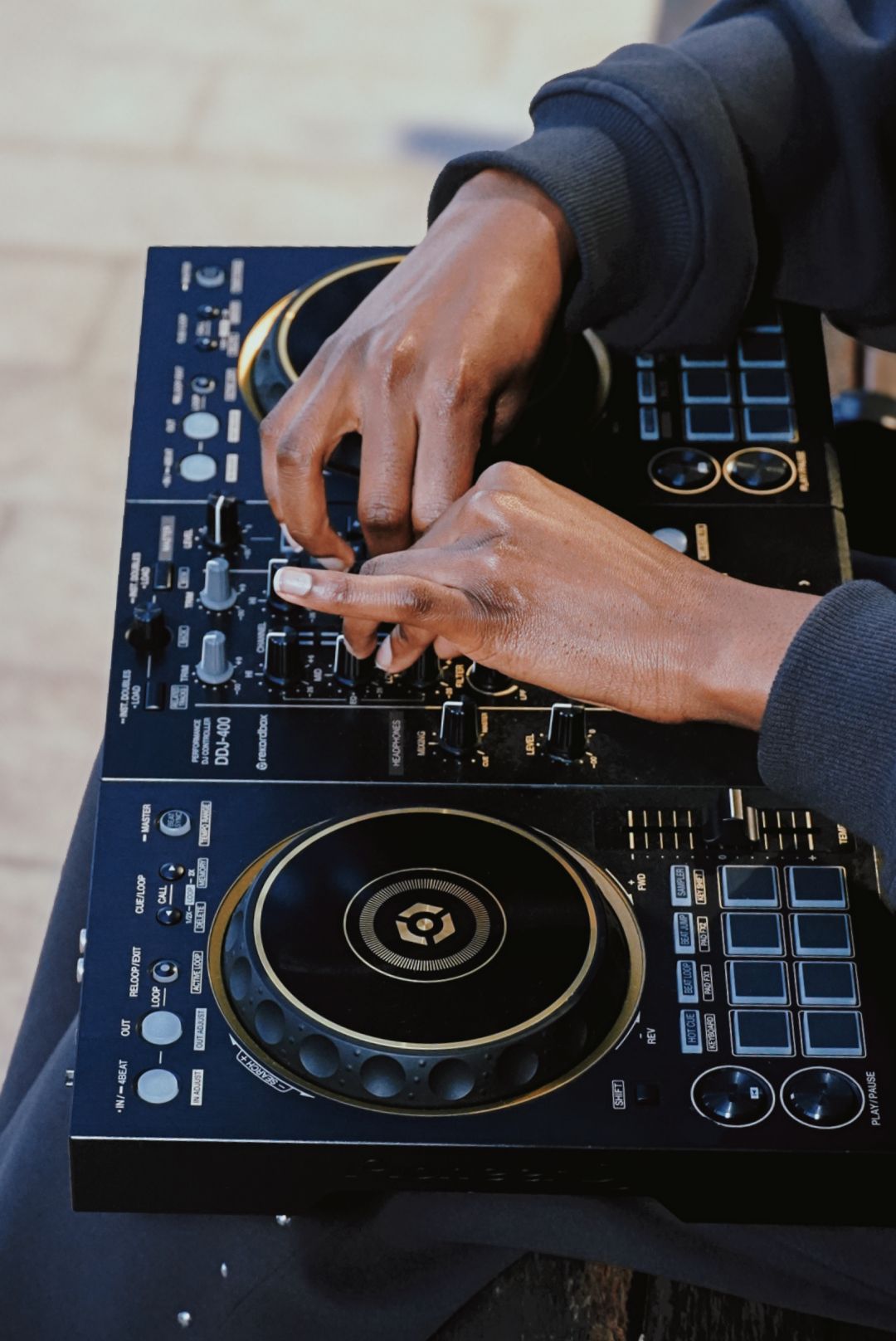 Close-up of hands operating Pioneer DDJ DJ controller.