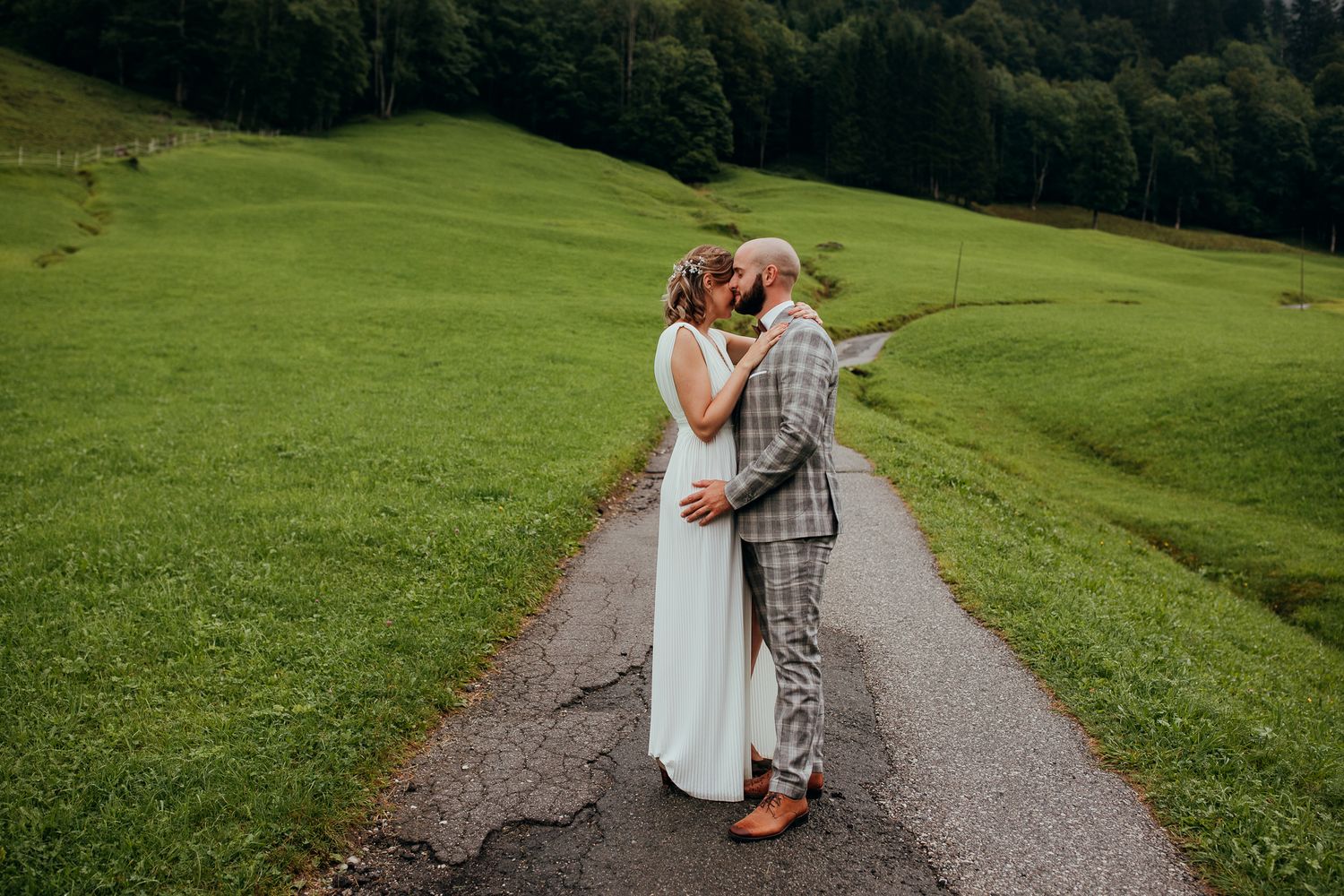 Intimer Kuss des Brautpaares auf einem ruhigen Weg in grüner Landschaft wärhend Hochzeitsshooting