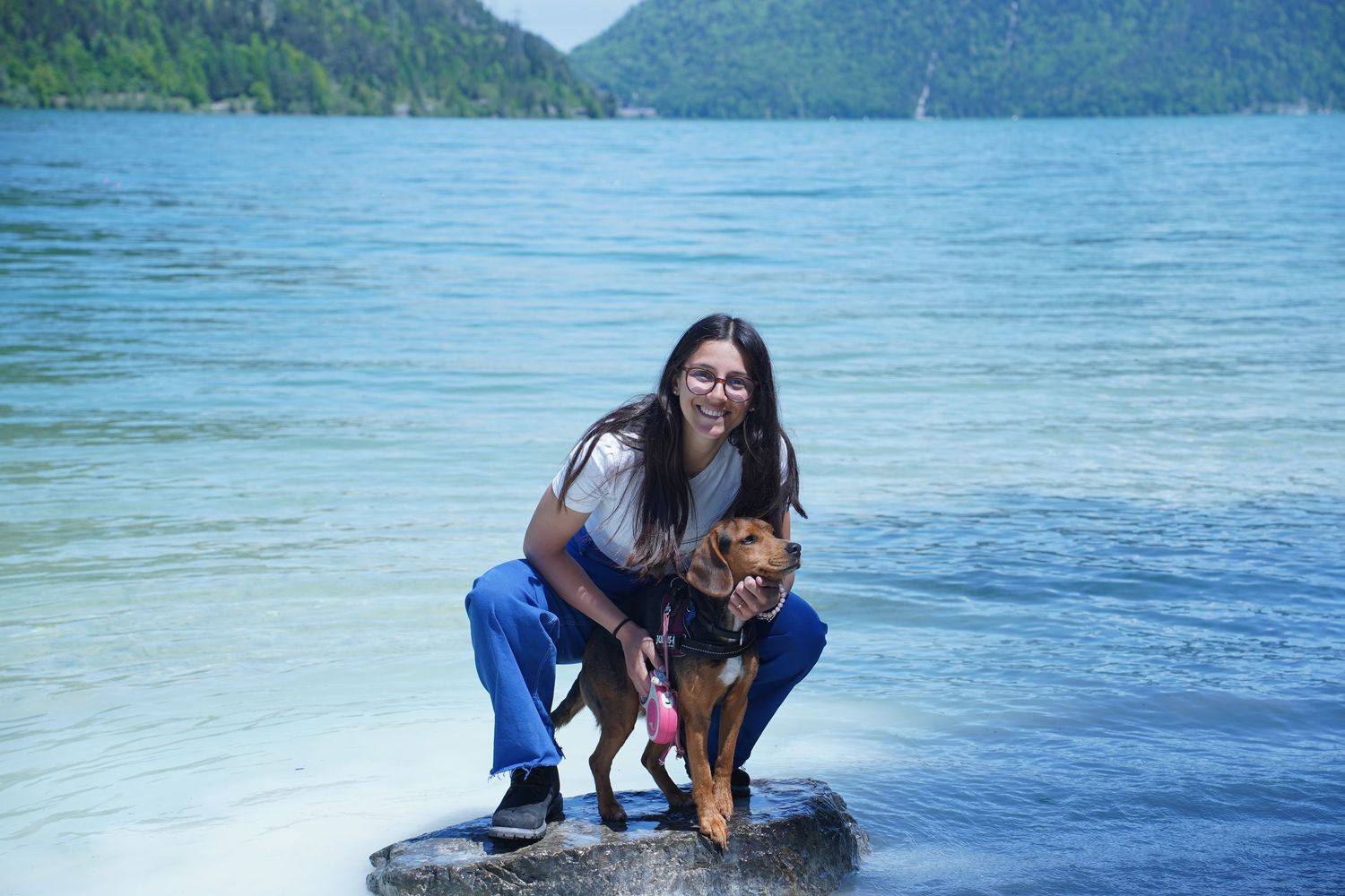 Person paddleboarding with their dog on calm mountain lake waters.