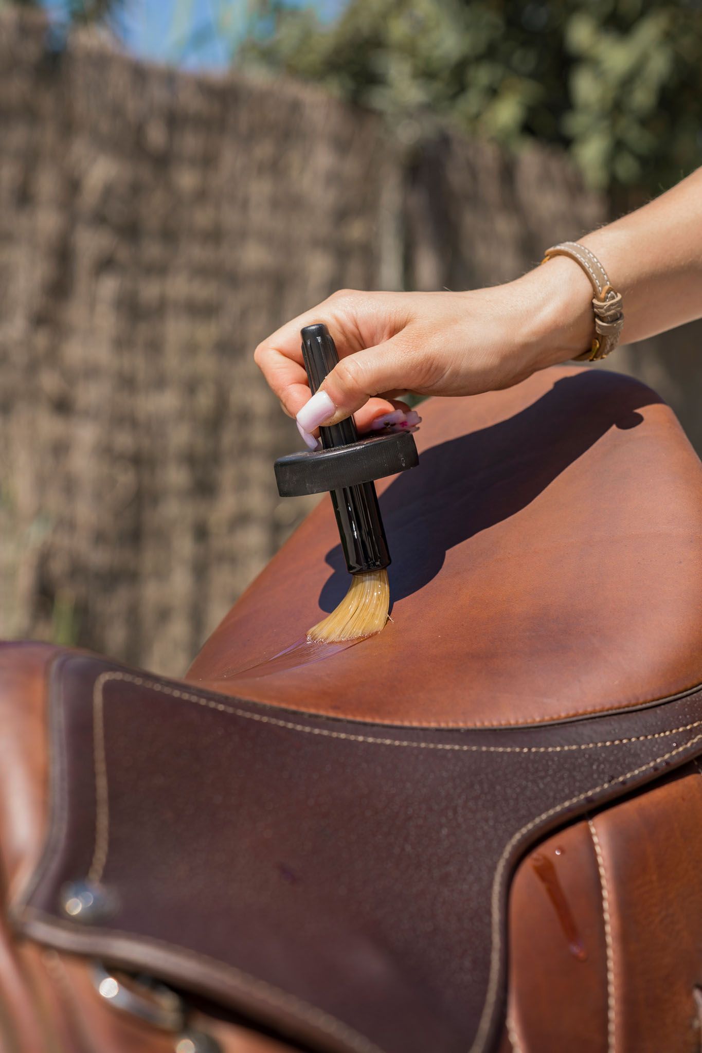 Close-up shot of a leather shoe being polished with a brush in natural lighting.