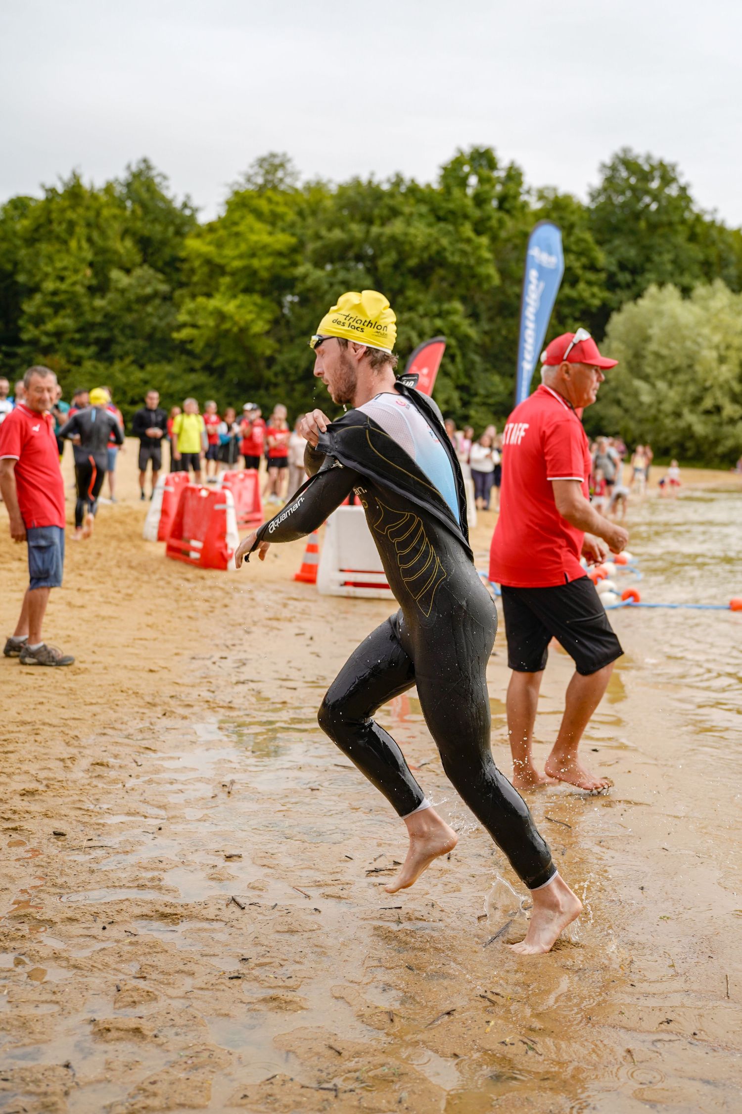 Athletes practice beach running drills on sandy terrain during outdoor training session.