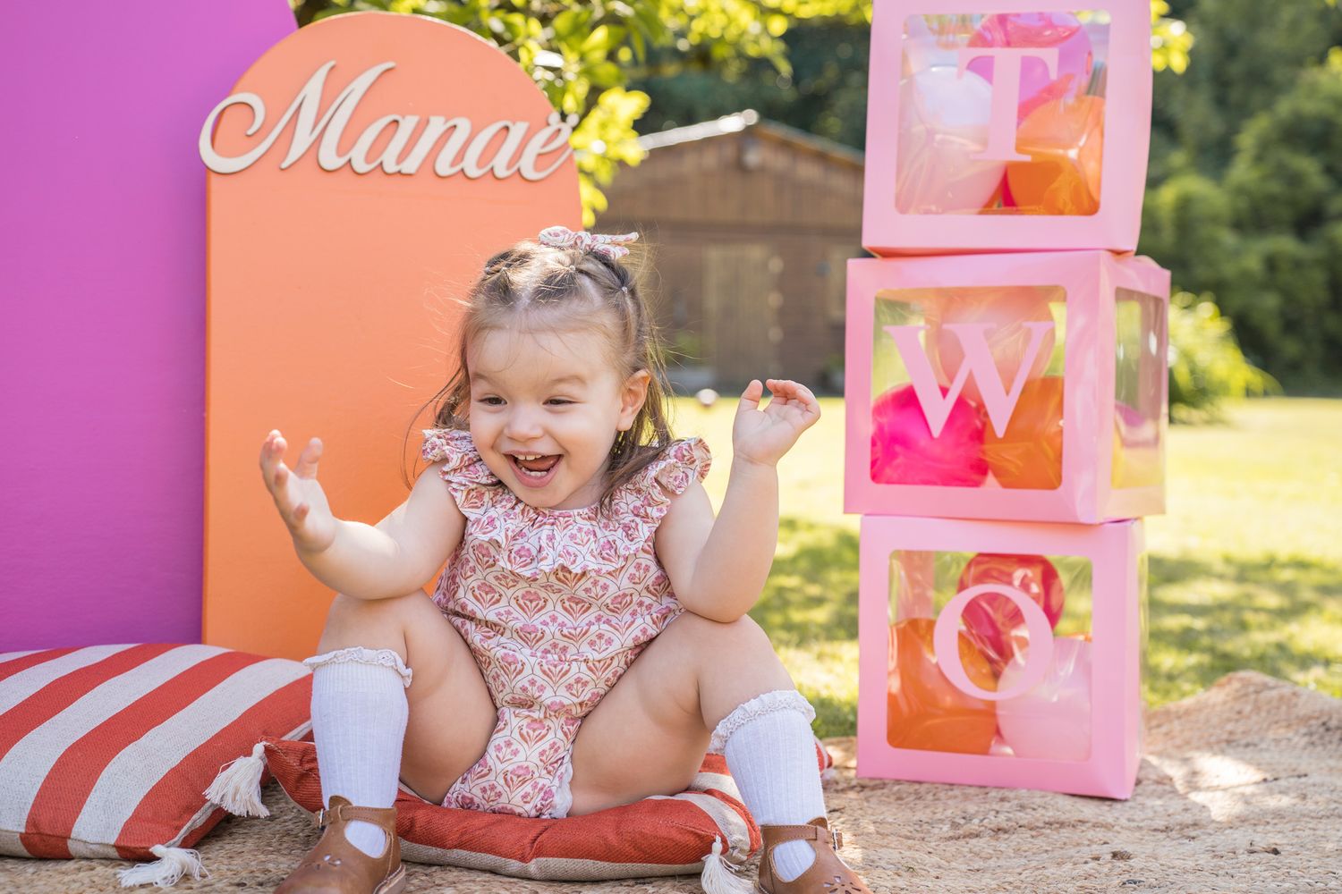 Pink and coral colored party decorations arranged outdoors on a sunny day.