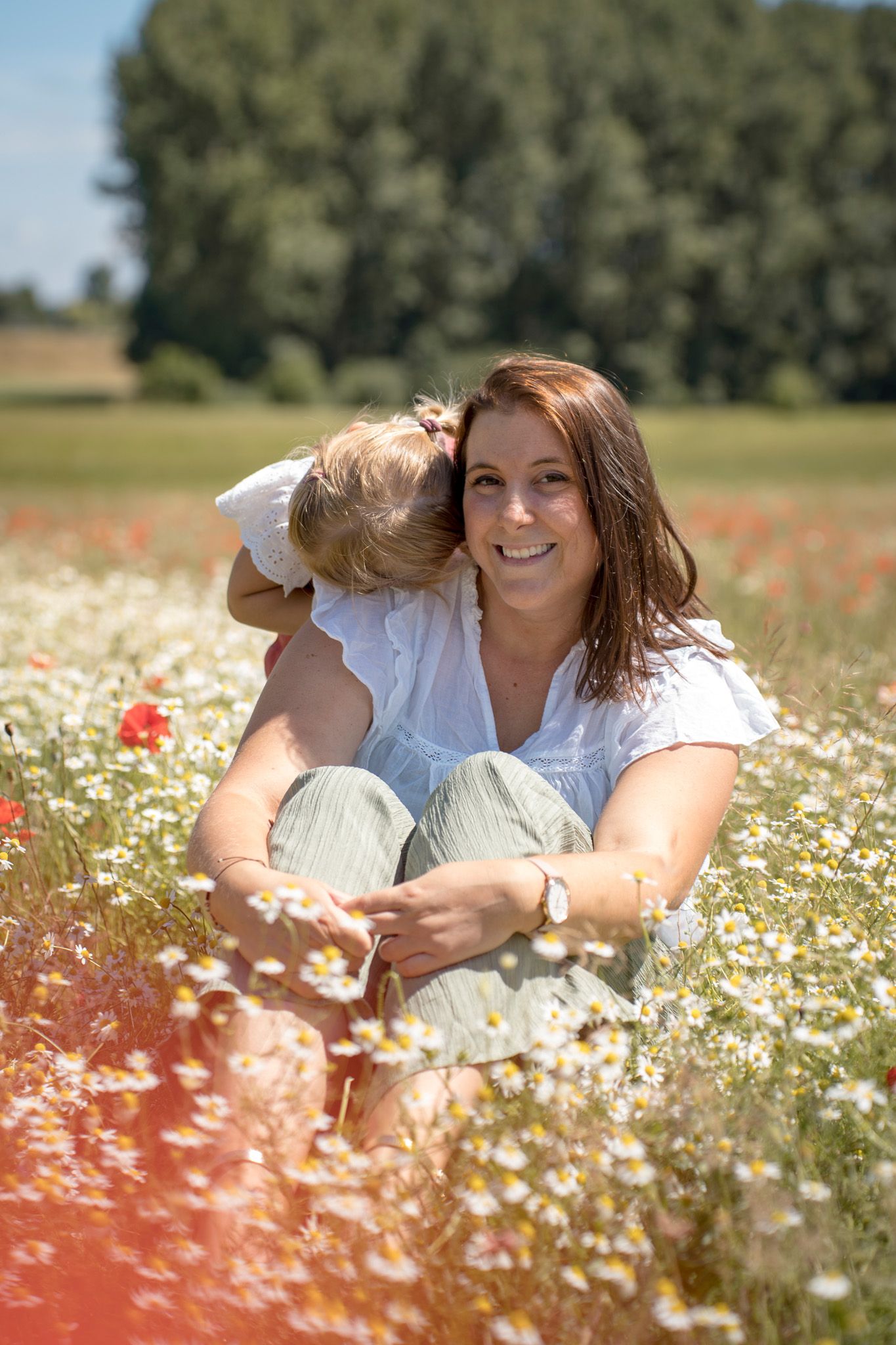 Tender moment captured in a blooming daisy field with red poppies.