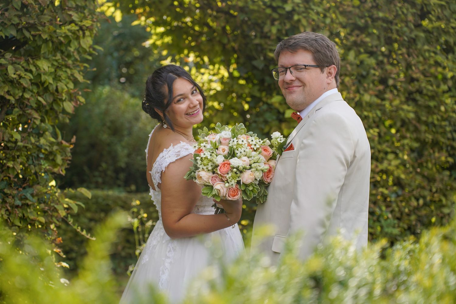 Couple shares intimate moments among lush garden greenery and flowers.