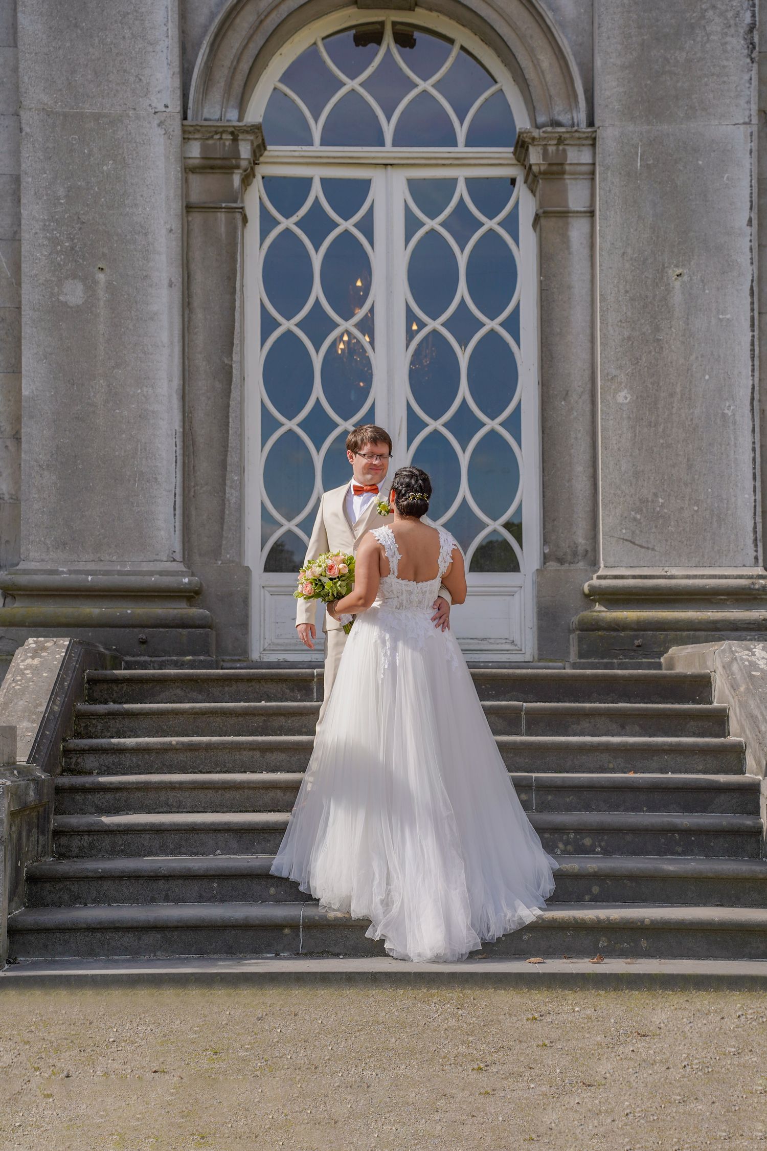 Elegant wedding photos captured against Gothic architecture with arched windows.
