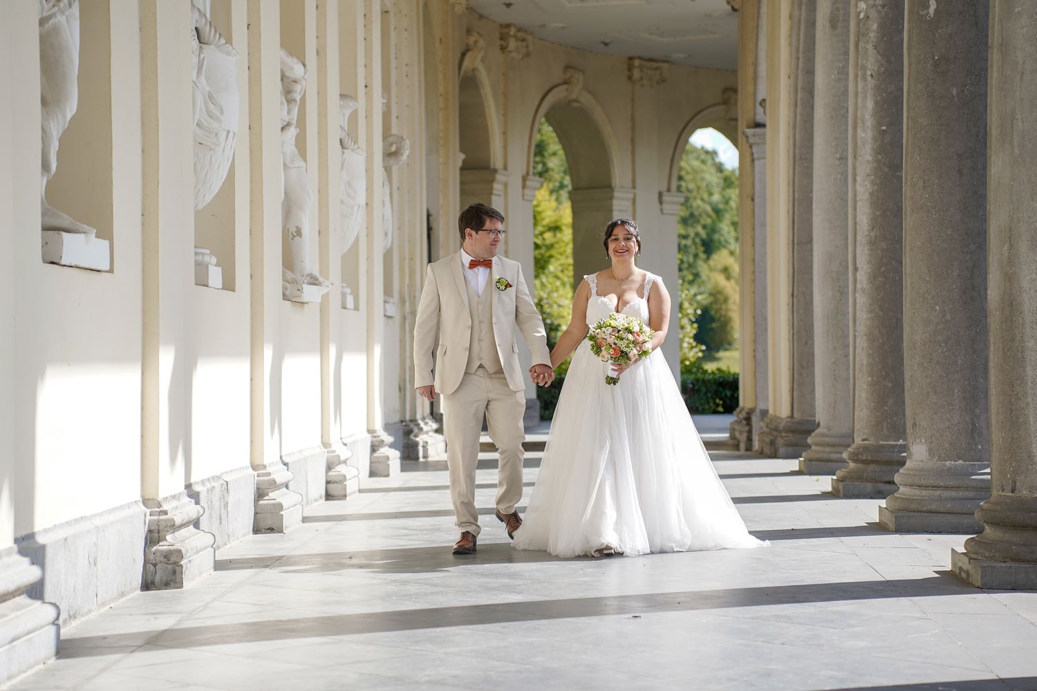 Wedding photography session in a classical colonnade with white pillars.