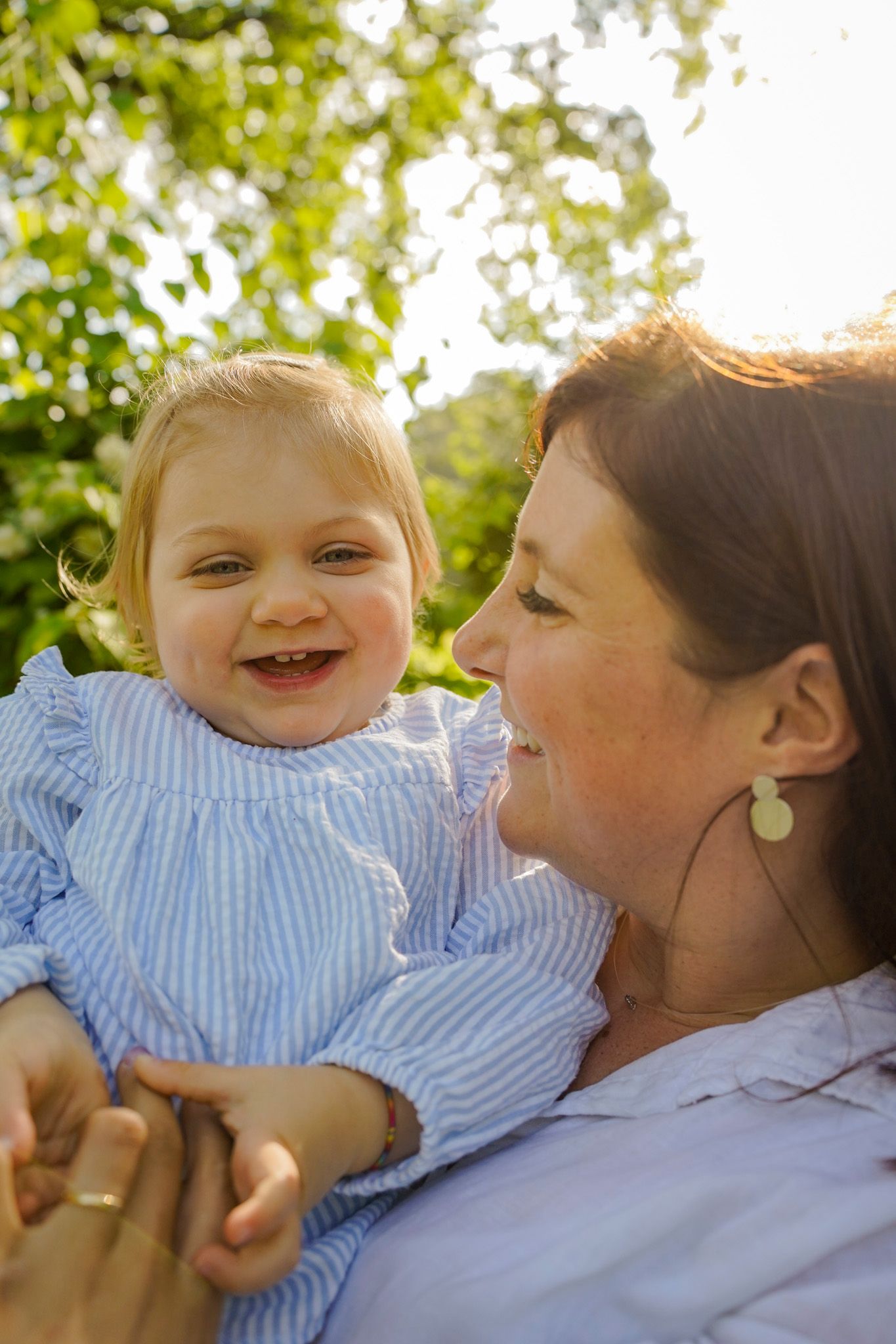 Sweet interactions captured in warm golden sunlight under leafy green trees.