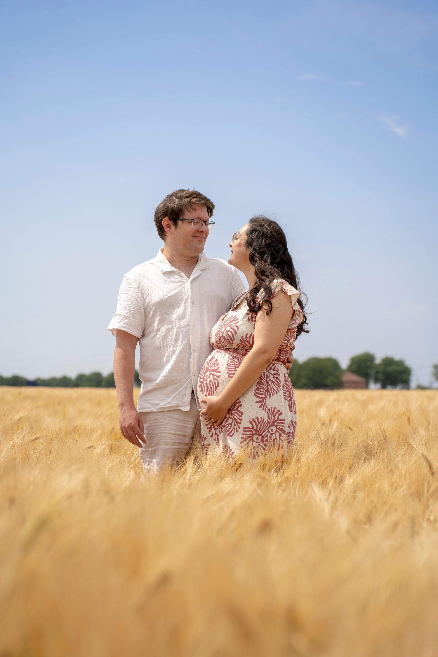 Couple shares tender moment together in a sun-lit wheat field.