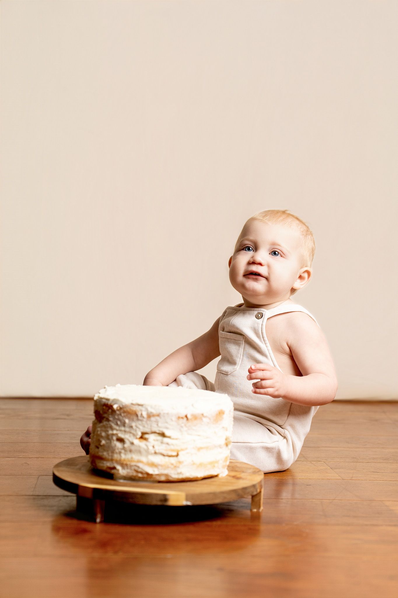 First birthday cake smash photography session with white layered cake.