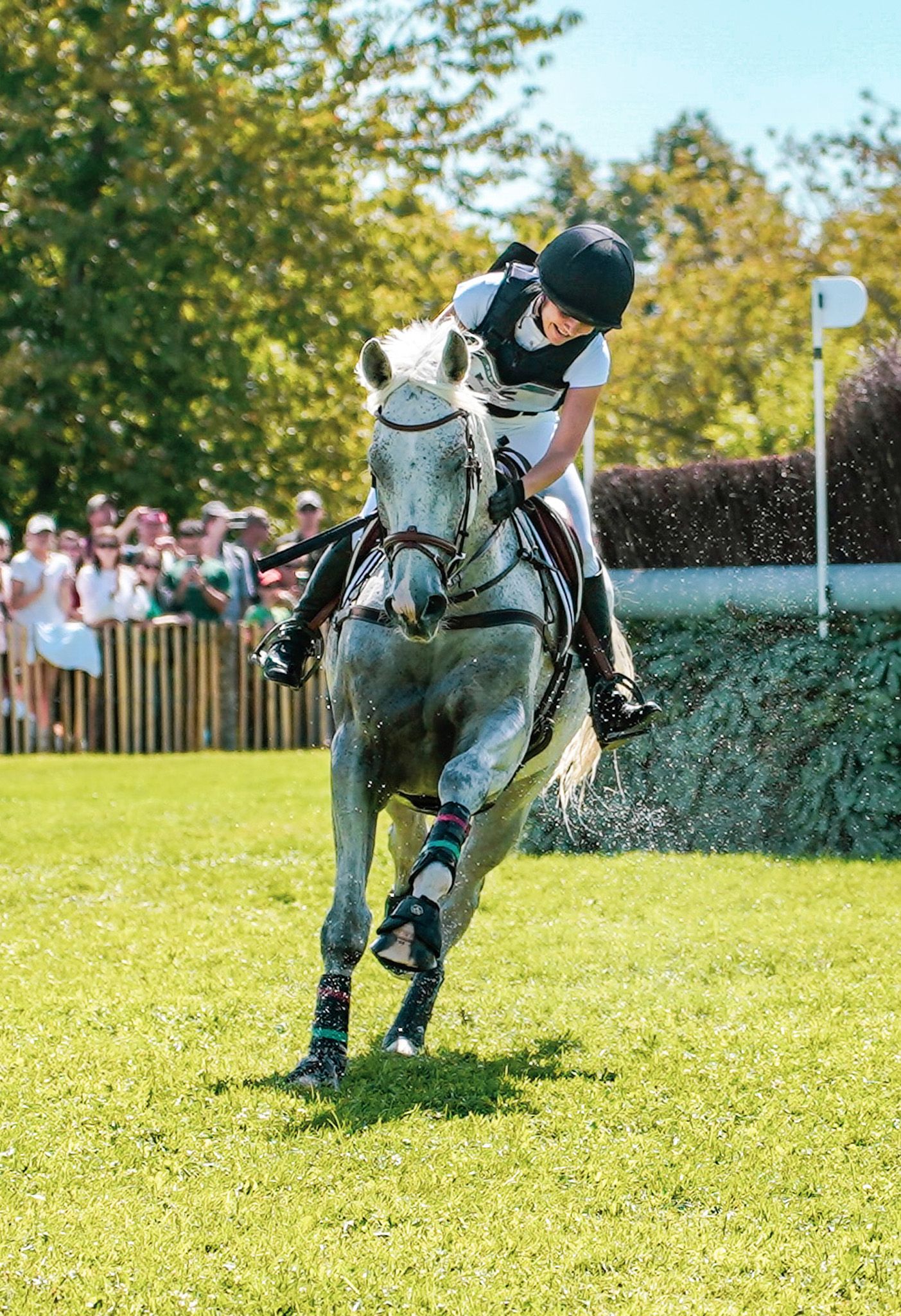 Grey horse and rider jumping over a challenging cross-country obstacle during equestrian competition.