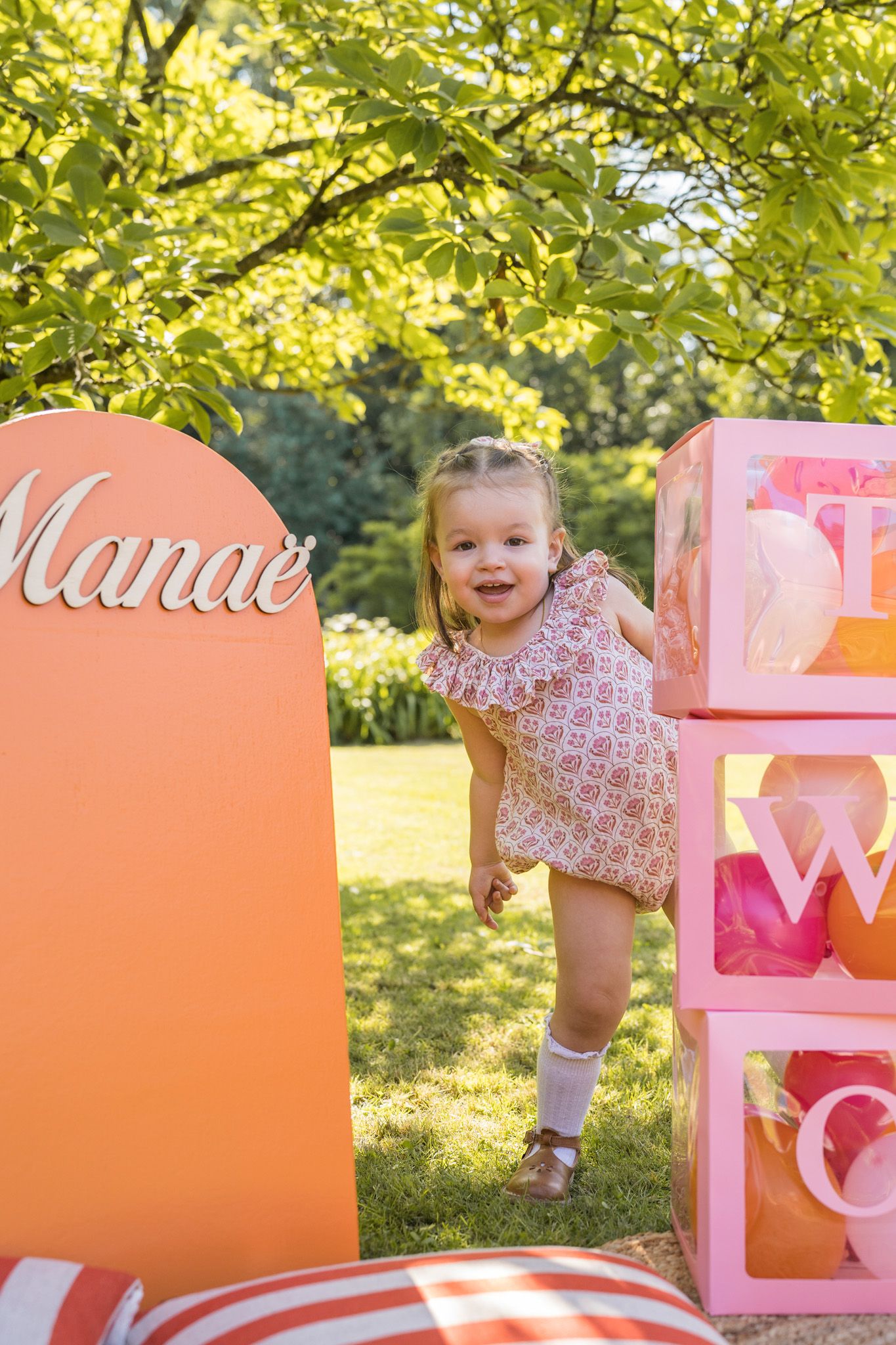 Festive outdoor scene with pink boxes and decorations against lush green foliage.