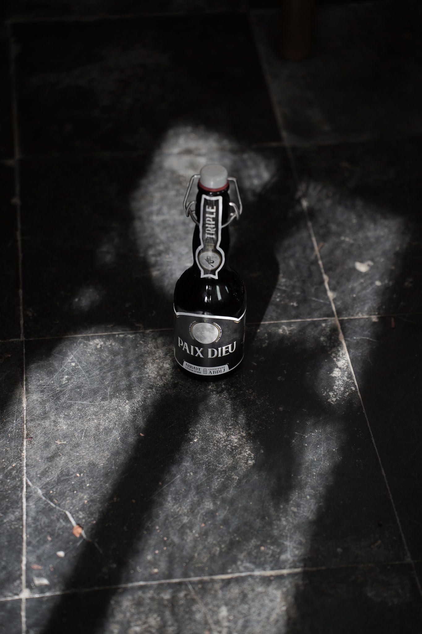 Dark artistic photo of a Bon Secours beer bottle on black surface.