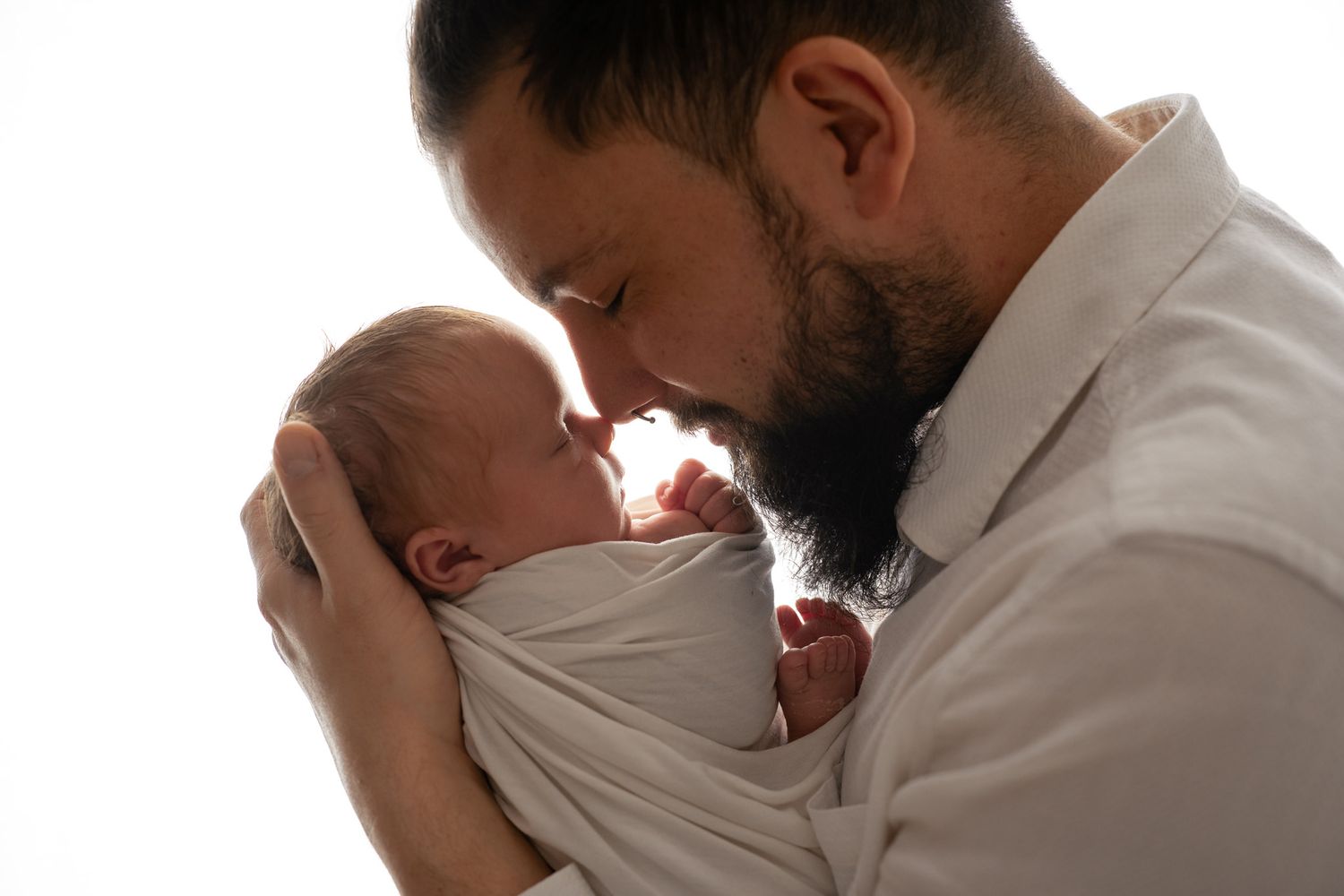 Tender family moment captured in white studio setting.