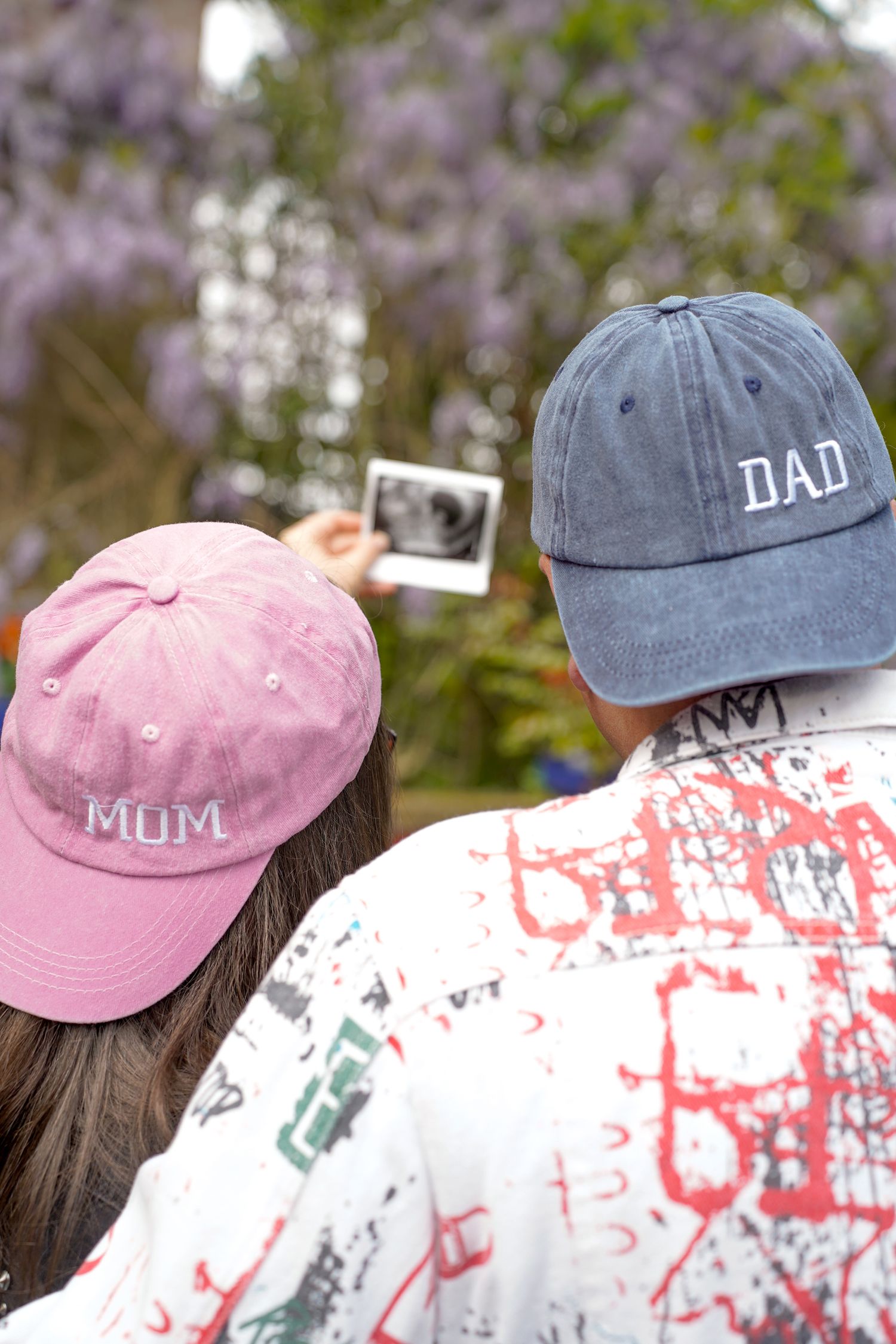 Baseball caps with 'Dad' and 'Mum' text against a floral background.