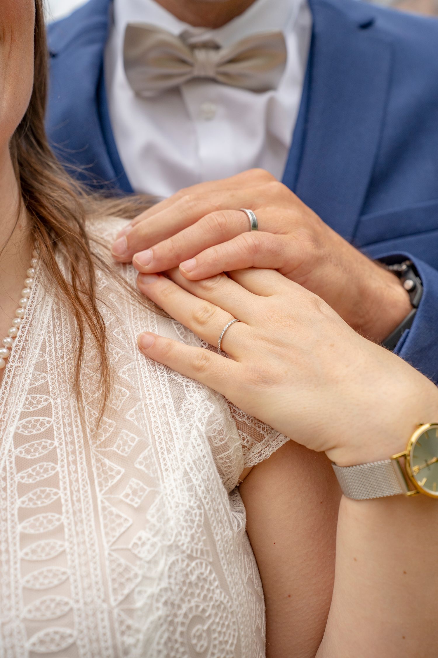 Detail shot of hands touching the intricate beaded pattern on a white wedding dress.