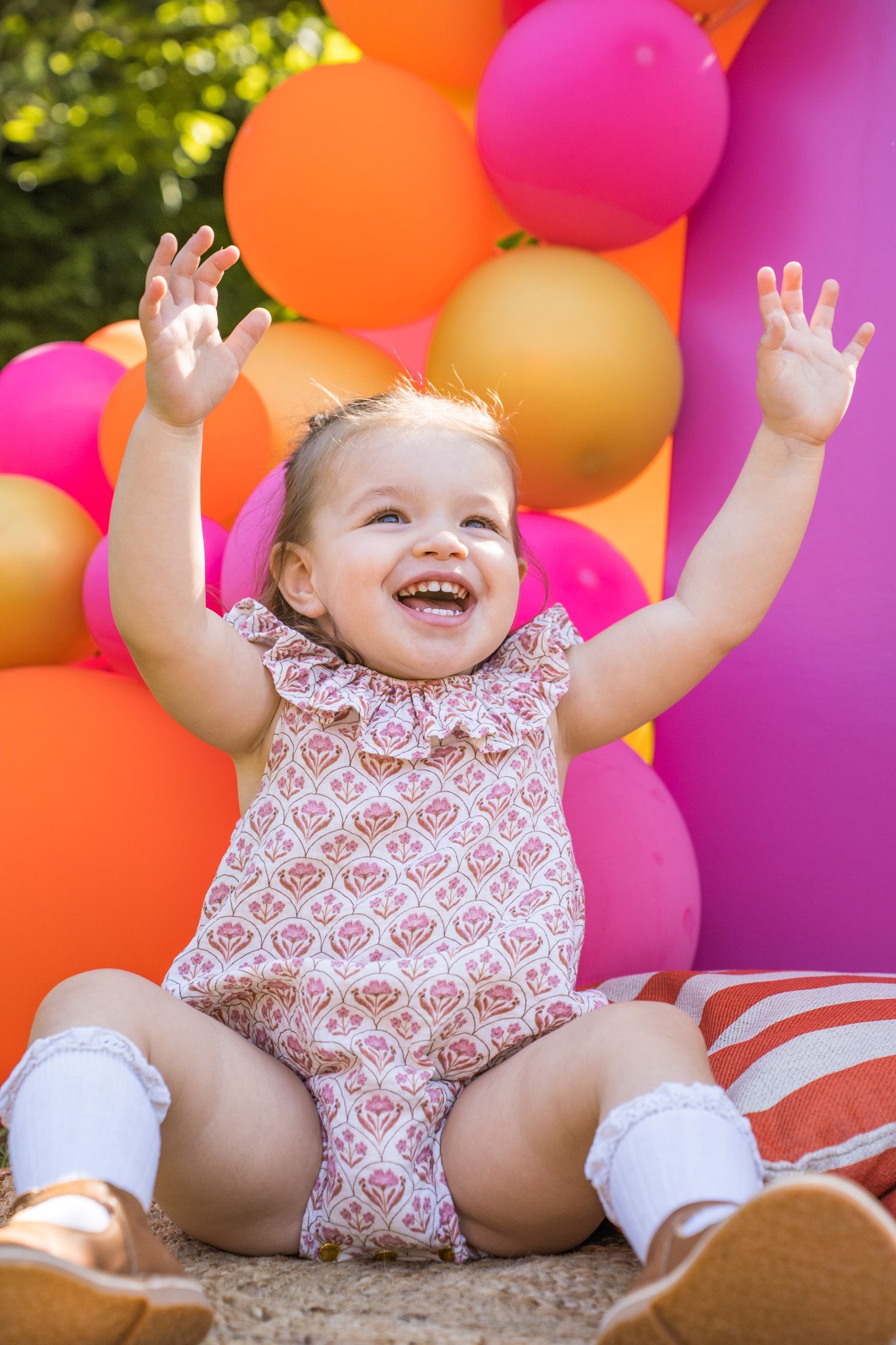 Festive outdoor celebration scene with vibrant pink and orange balloons against natural greenery.