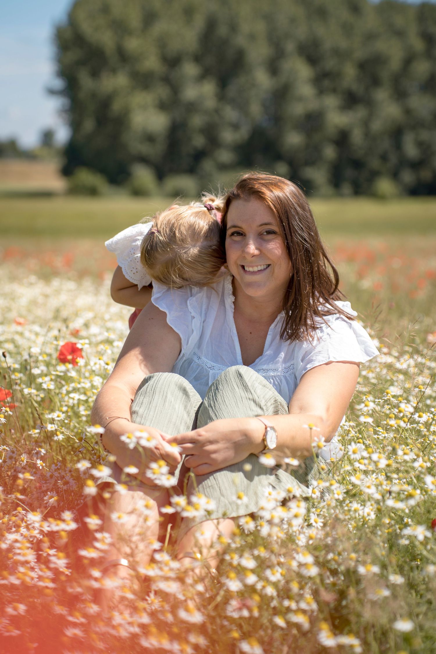 Sweet summer moments shared in a field of daisies and poppies on a sunny afternoon.