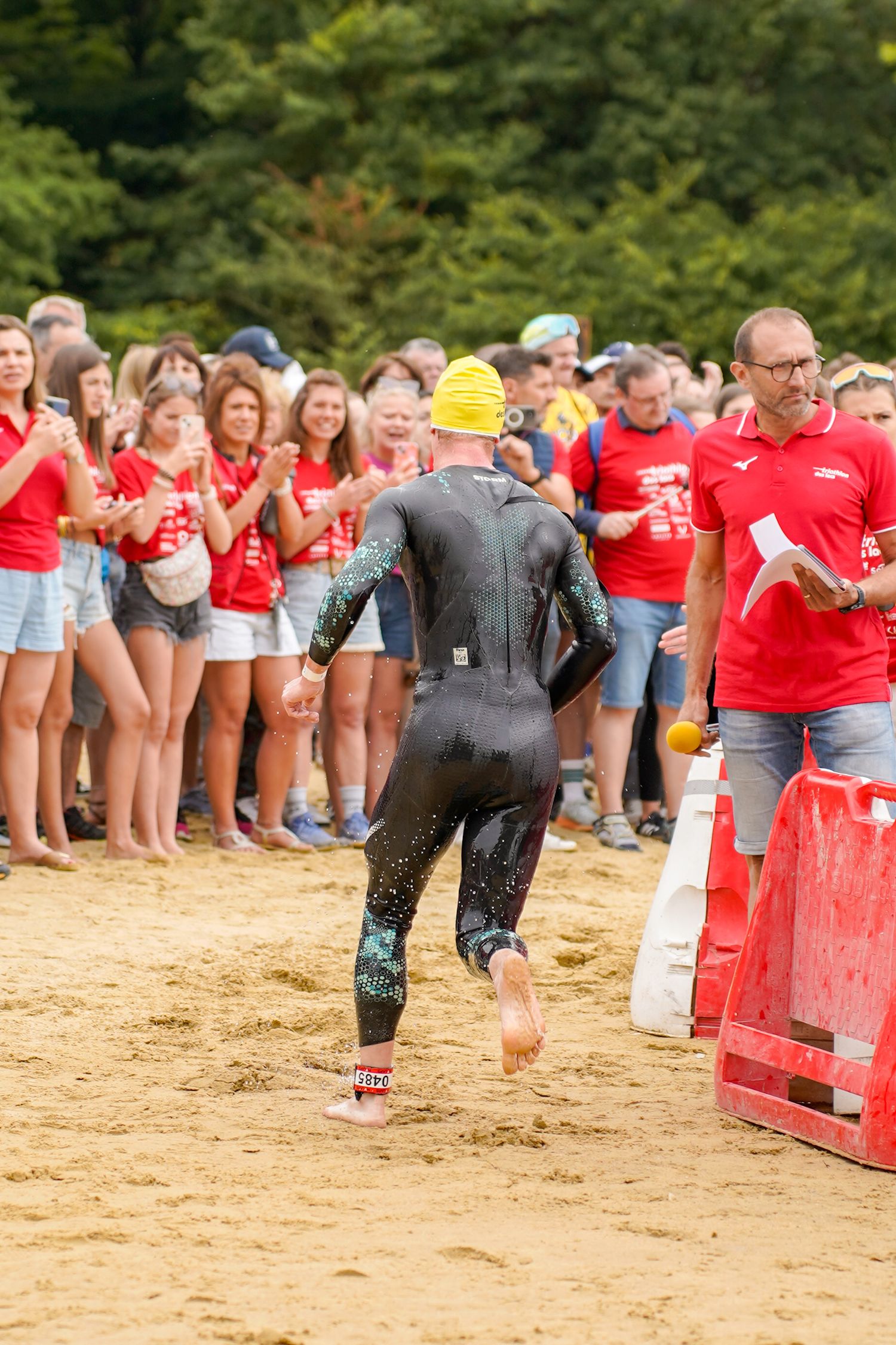 Athletes competing in obstacle course race on sandy beach.