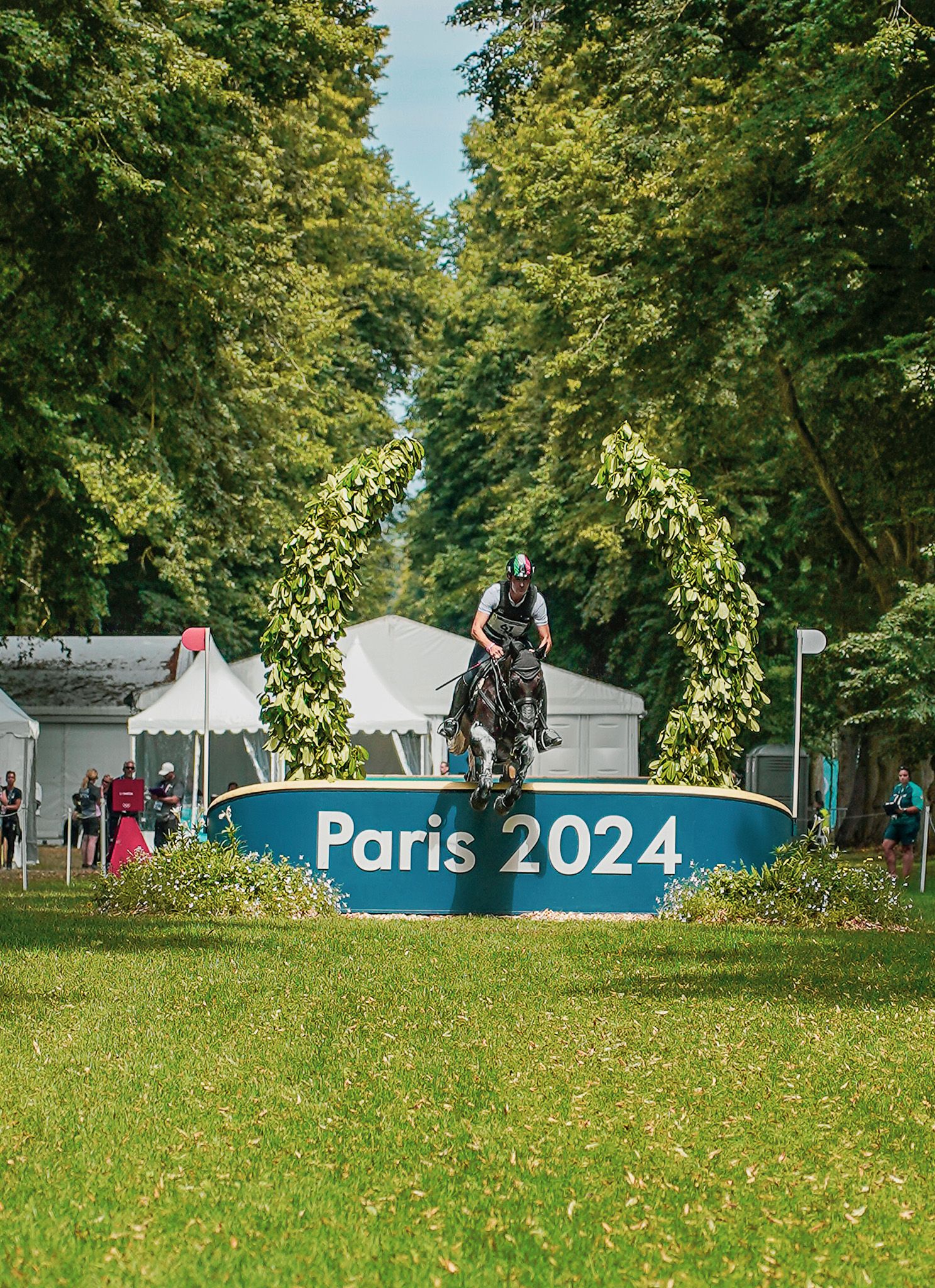 Green field with Paris 2024 Olympic signage visible in the background.