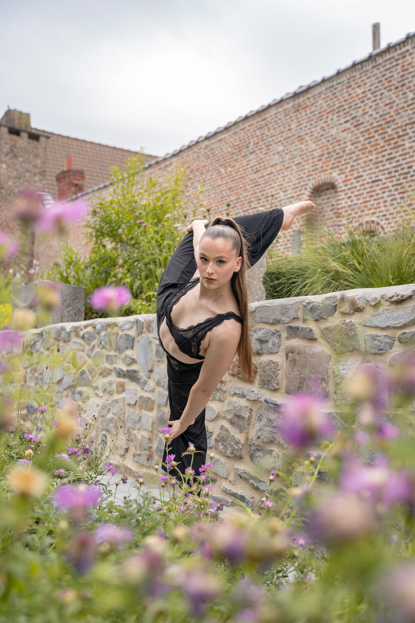 Modern dance movements captured among purple flowers and brick walls.