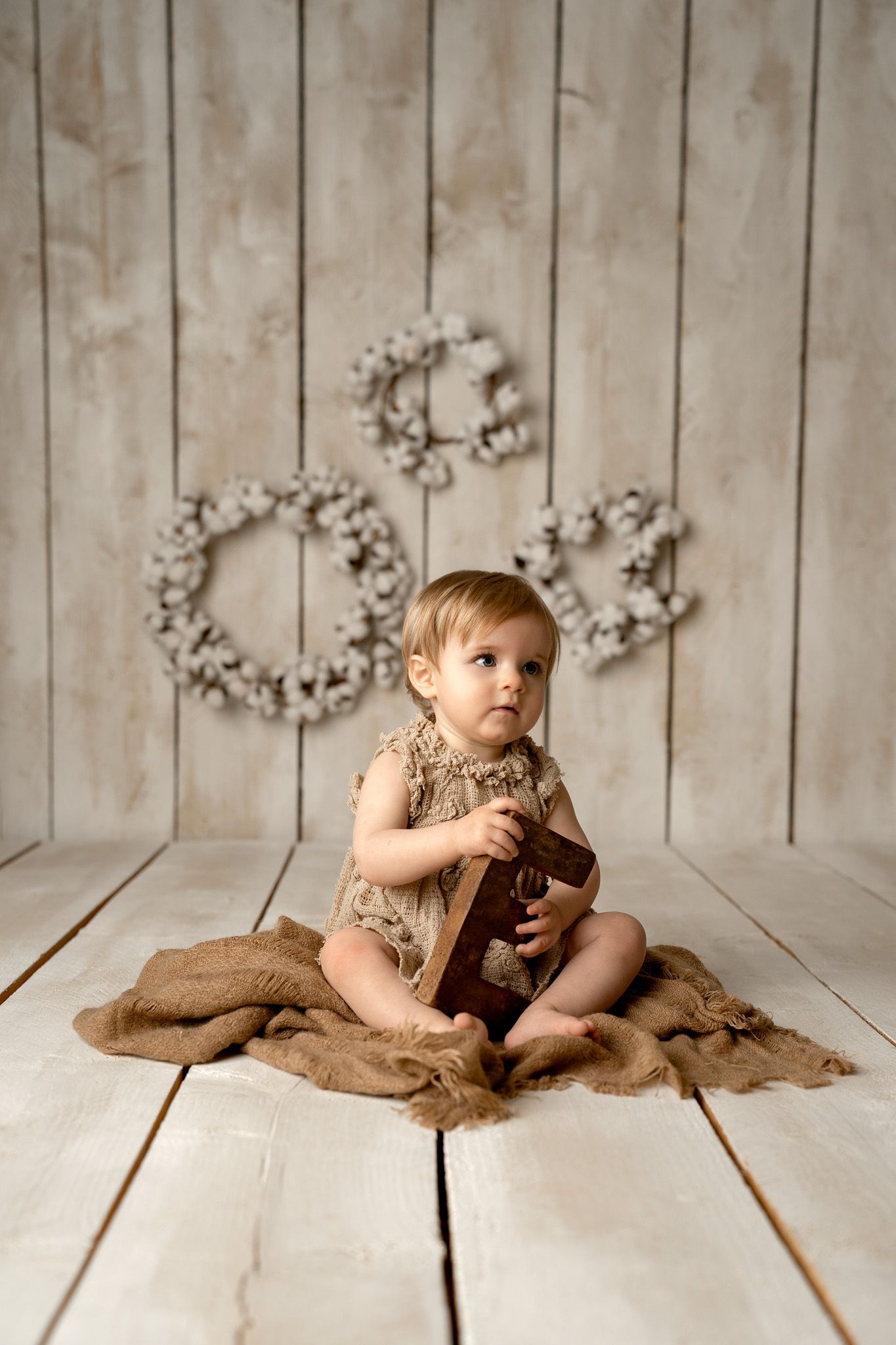 Rustic photography setup with wooden backdrop and cotton decorations.