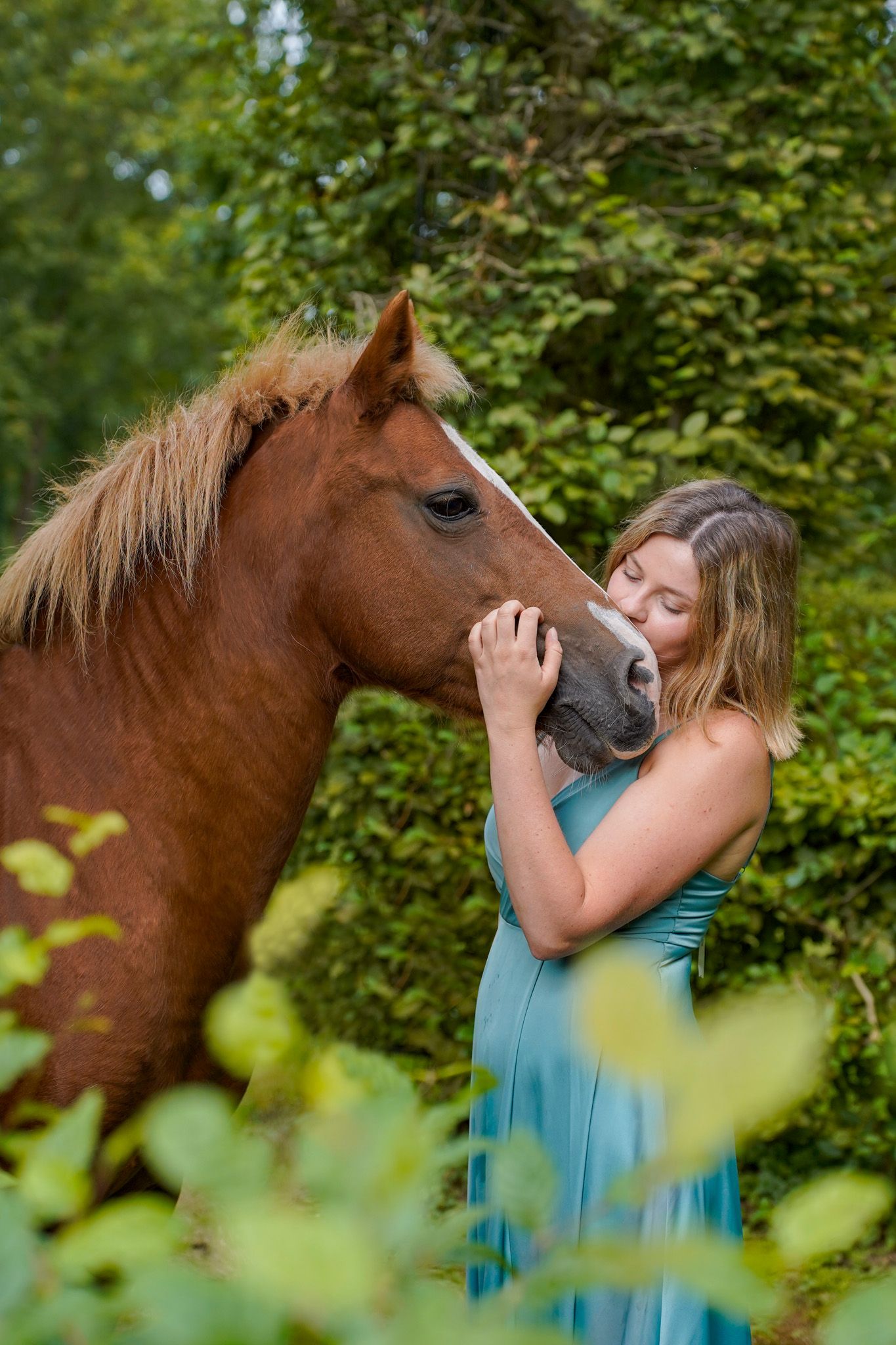 Intimate moment between horse and companion in lush green garden setting.