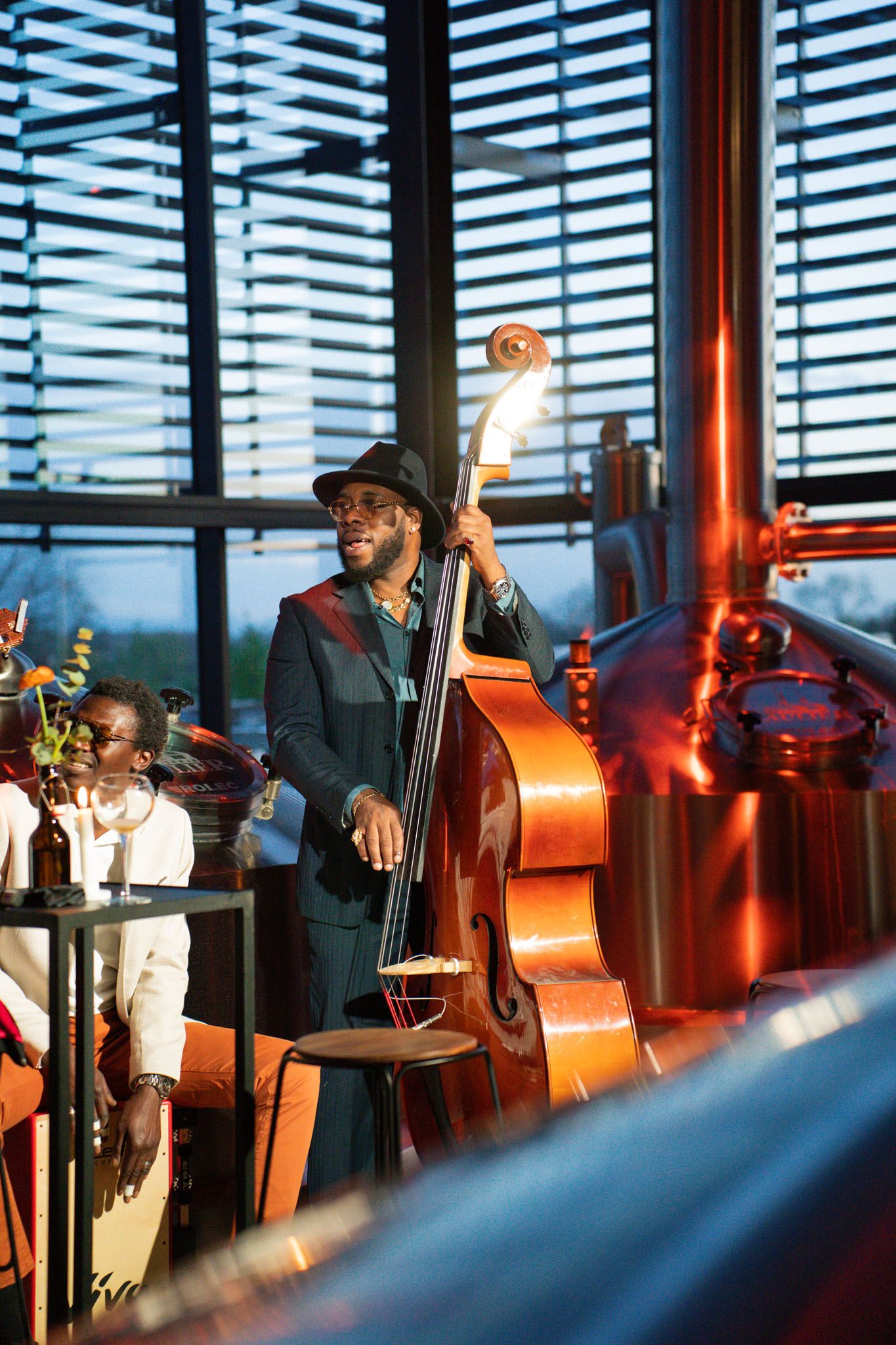 Jazz musicians perform with upright bass in a modern venue with blue-tinted windows.