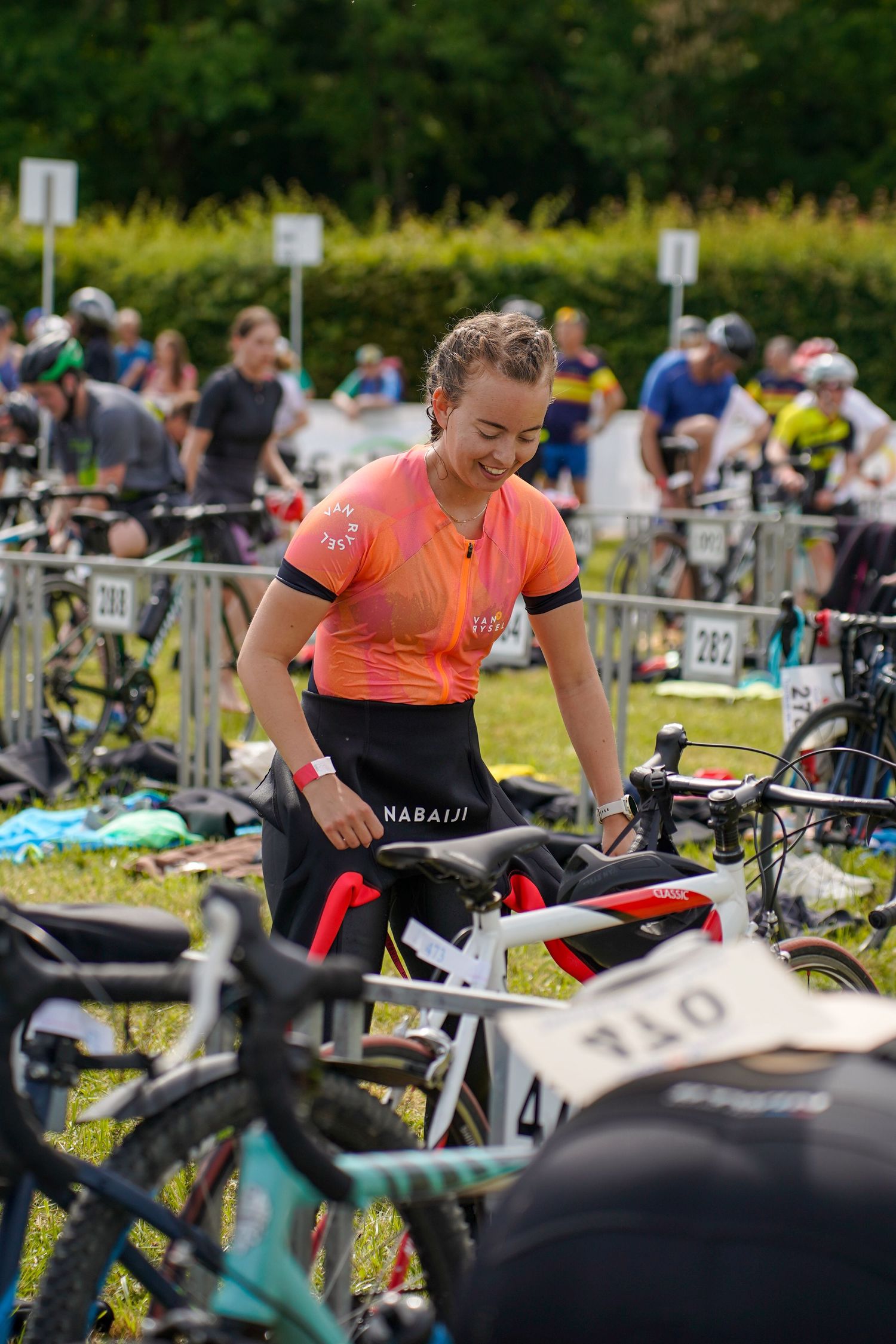 Athletes preparing their bikes in transition area during triathlon event.
