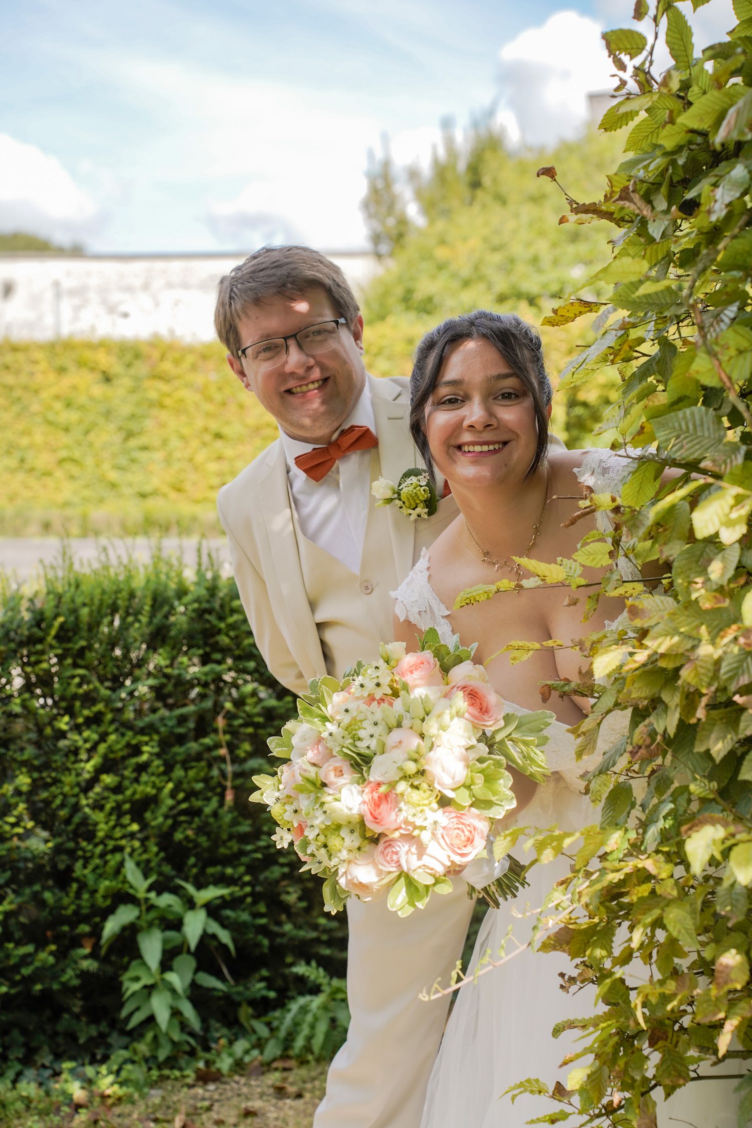 A romantic wedding photoshoot in a garden setting with beautiful peach and white floral bouquet.