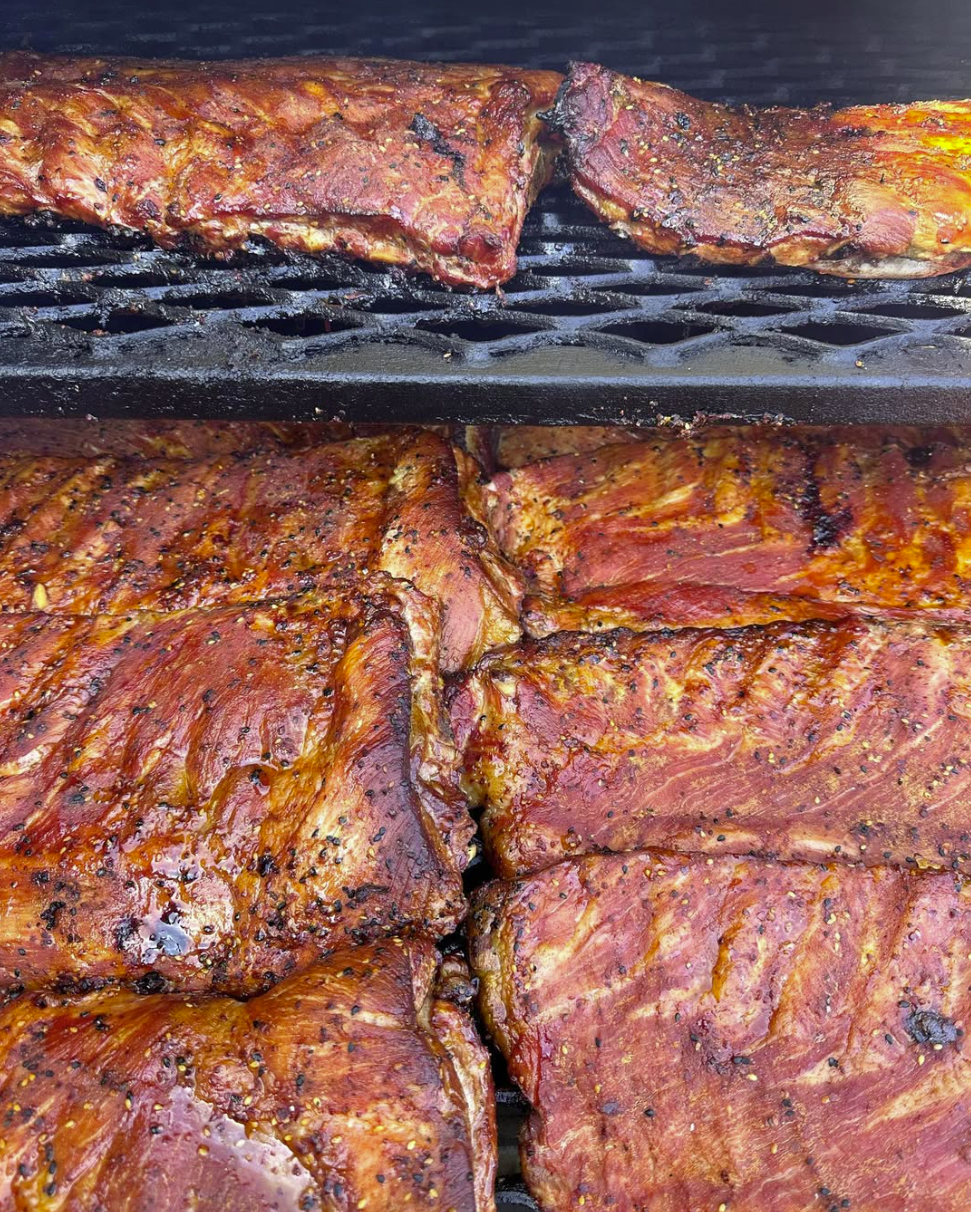 Smoky BBQ pork ribs slow-cooked on a grill, glazed with rich caramelized seasoning, perfect for a backyard barbecue.
