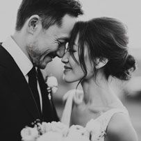 Black and white wedding photo of a couple sharing an intimate moment, bride holding a bouquet.