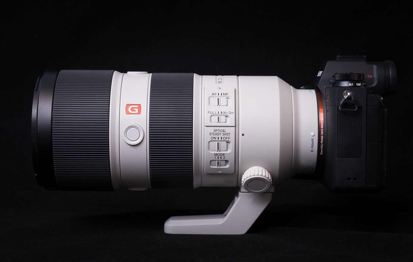 Close-up view of a professional white telephoto lens with red and black markings showing focal length details.
