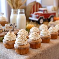 Autumn cupcakes with white frosting displayed on burlap, with milk jars and a red toy truck in the background.