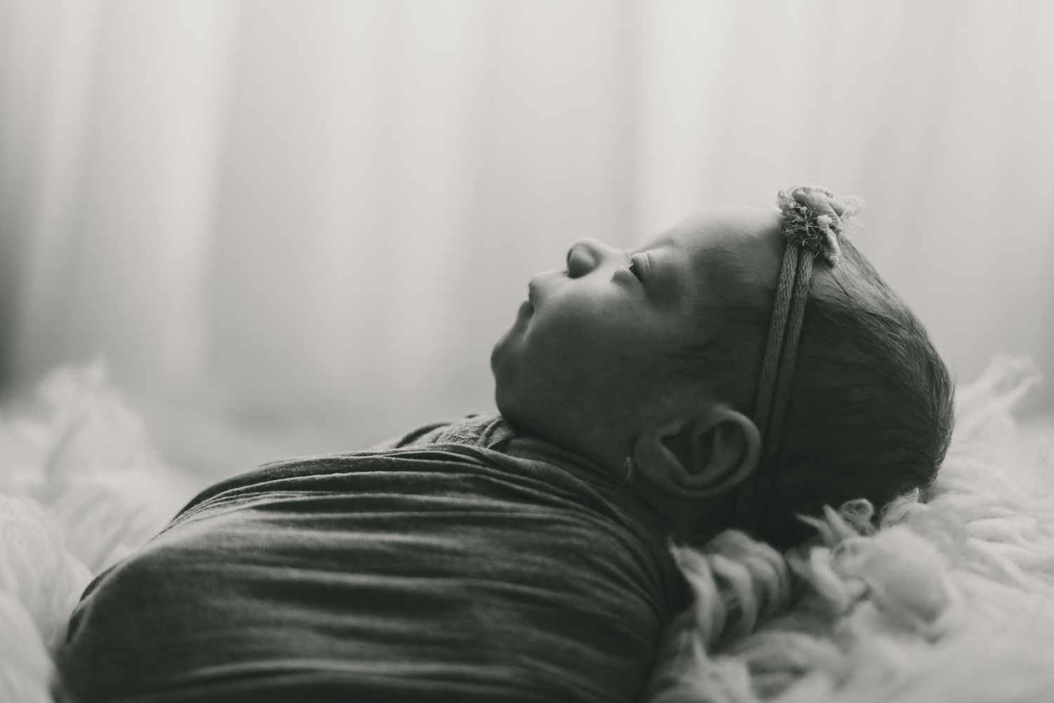 Black and white image of a swaddled newborn baby in photo taken by Little Buckaroo Portrait Co. in East Texas
