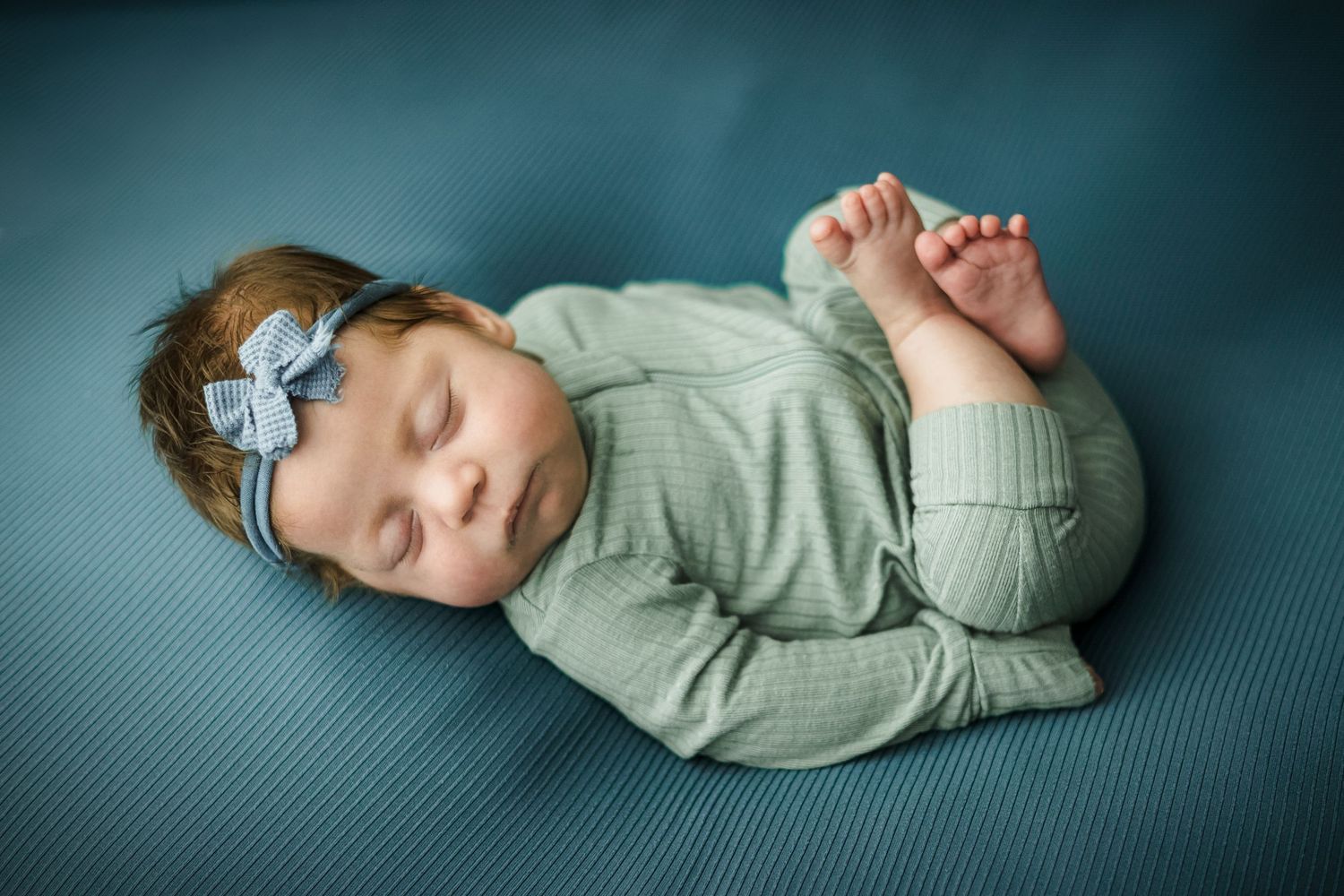 Newborn baby laying on back with legs crossed in photo taken by Little Buckaroo Portrait Co. in East Texas.