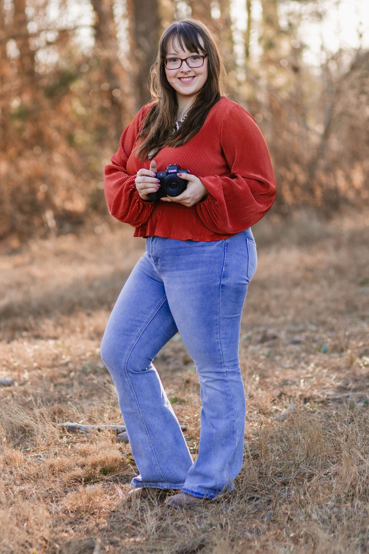 A woman standing in an East Texas field with a camera in photo taken by Little Buckaroo Portrait Co.