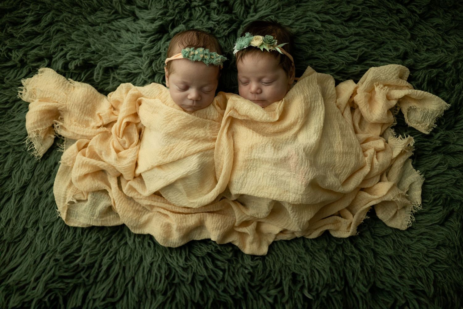 Newborn twins laying together with peach fabric covering them in photo taken by Little Buckaroo Portrait Co. in East Texas.