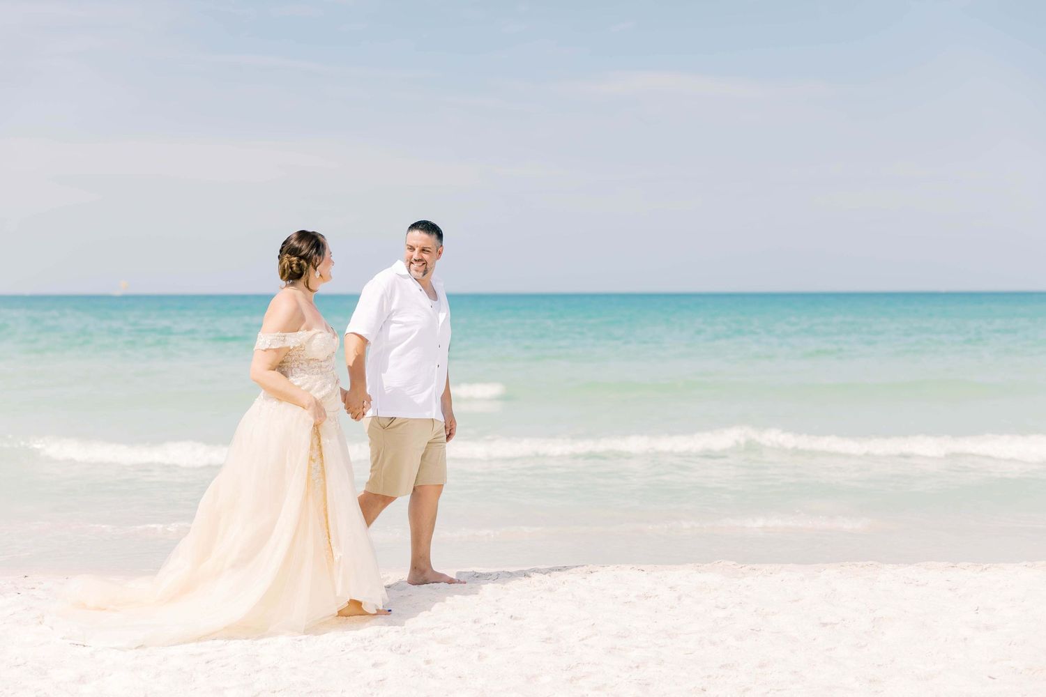 Couple enjoying a romantic moment on a pristine white sand beach with turquoise ocean backdrop.