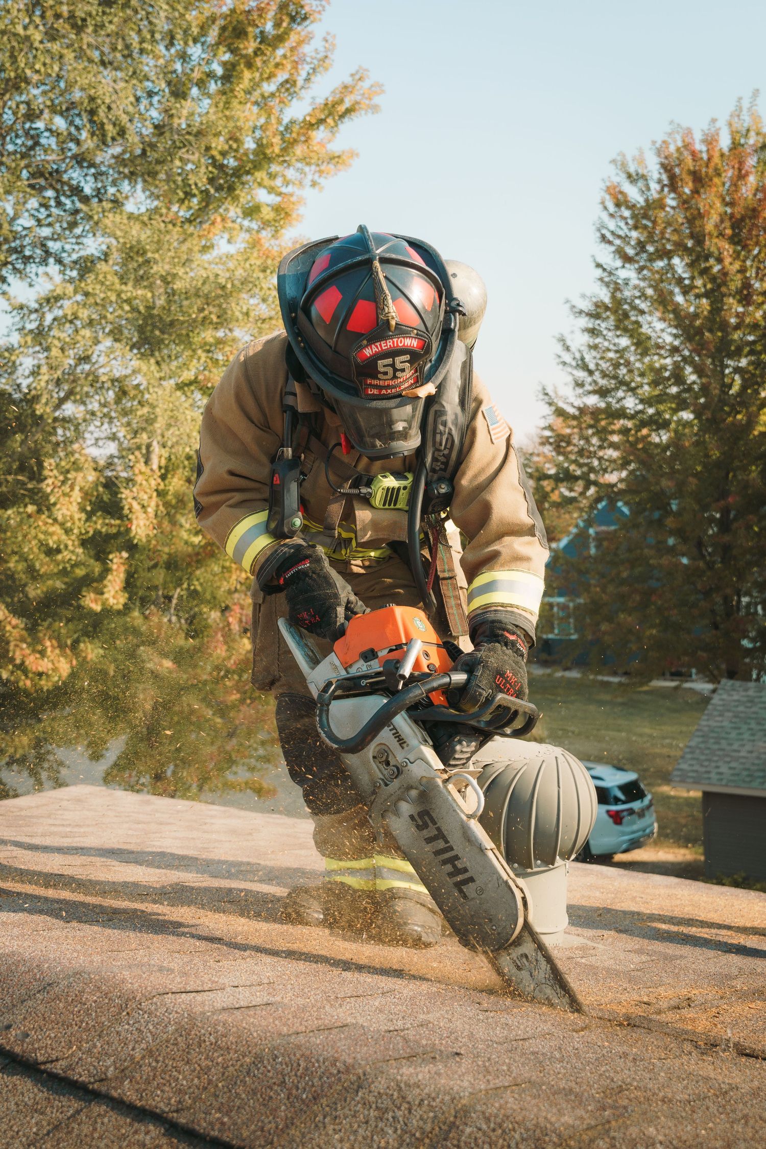 Firefighter in protective gear uses a powerful chainsaw outdoors during an emergency response operation.
