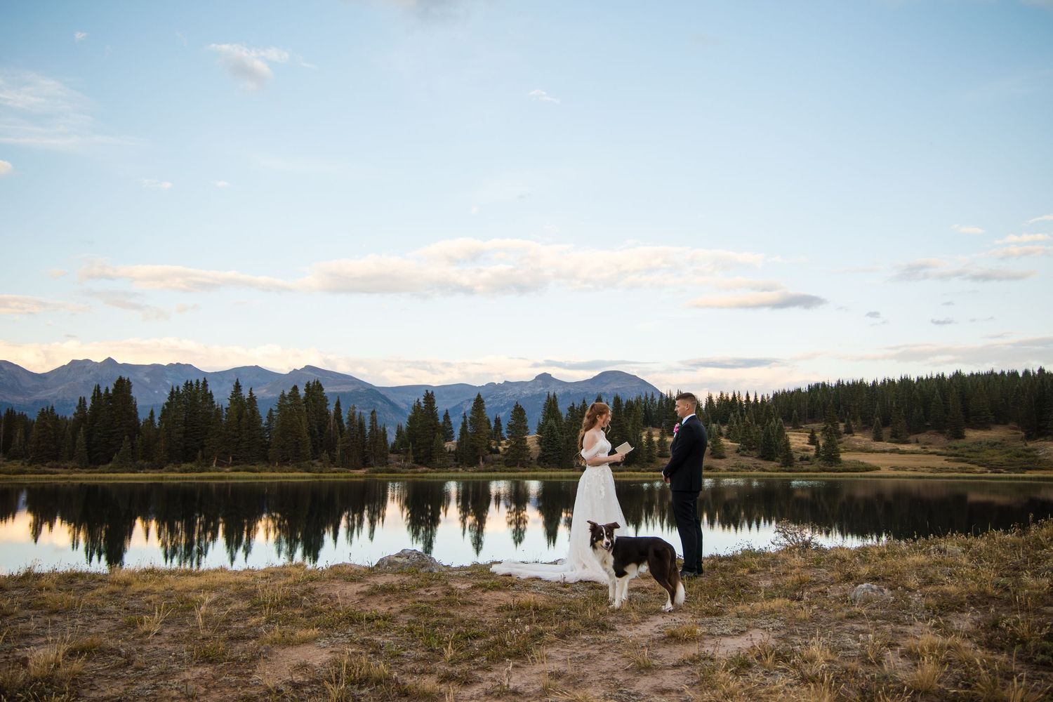 A panoramic mountain landscape with snow-capped peaks, evergreen forests, and a serene lake reflecting the scenery.