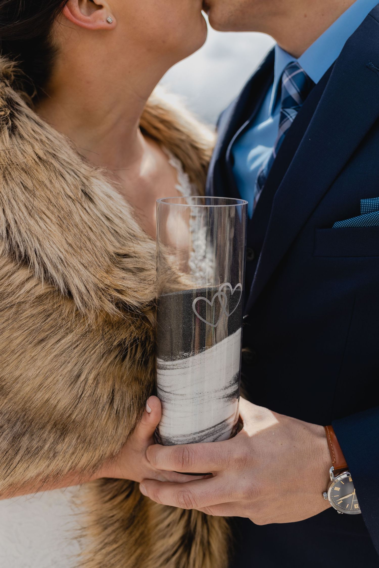 Close-up of couple sharing a toast with etched glass while wearing formal attire.