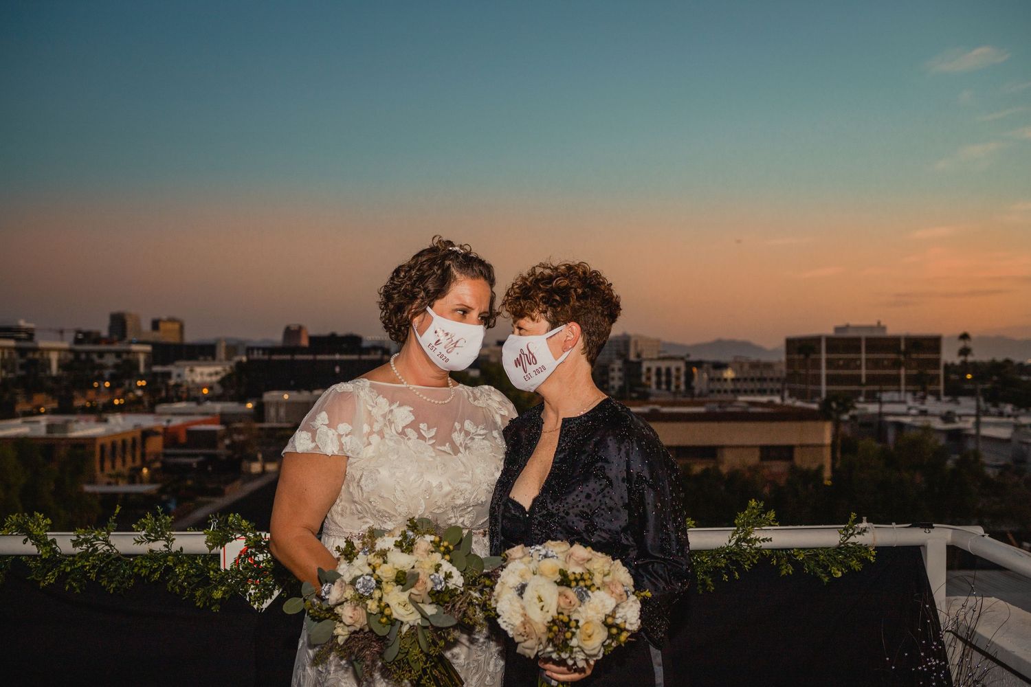two brides staring at each other lovingly with their covid masks on