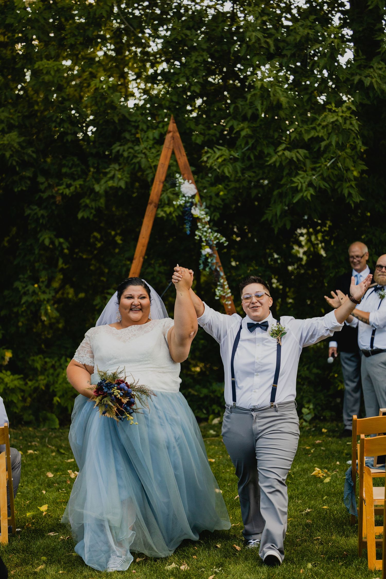 queer couple holding hands walking down the aisle captured by a Colorado Elopement Photographer