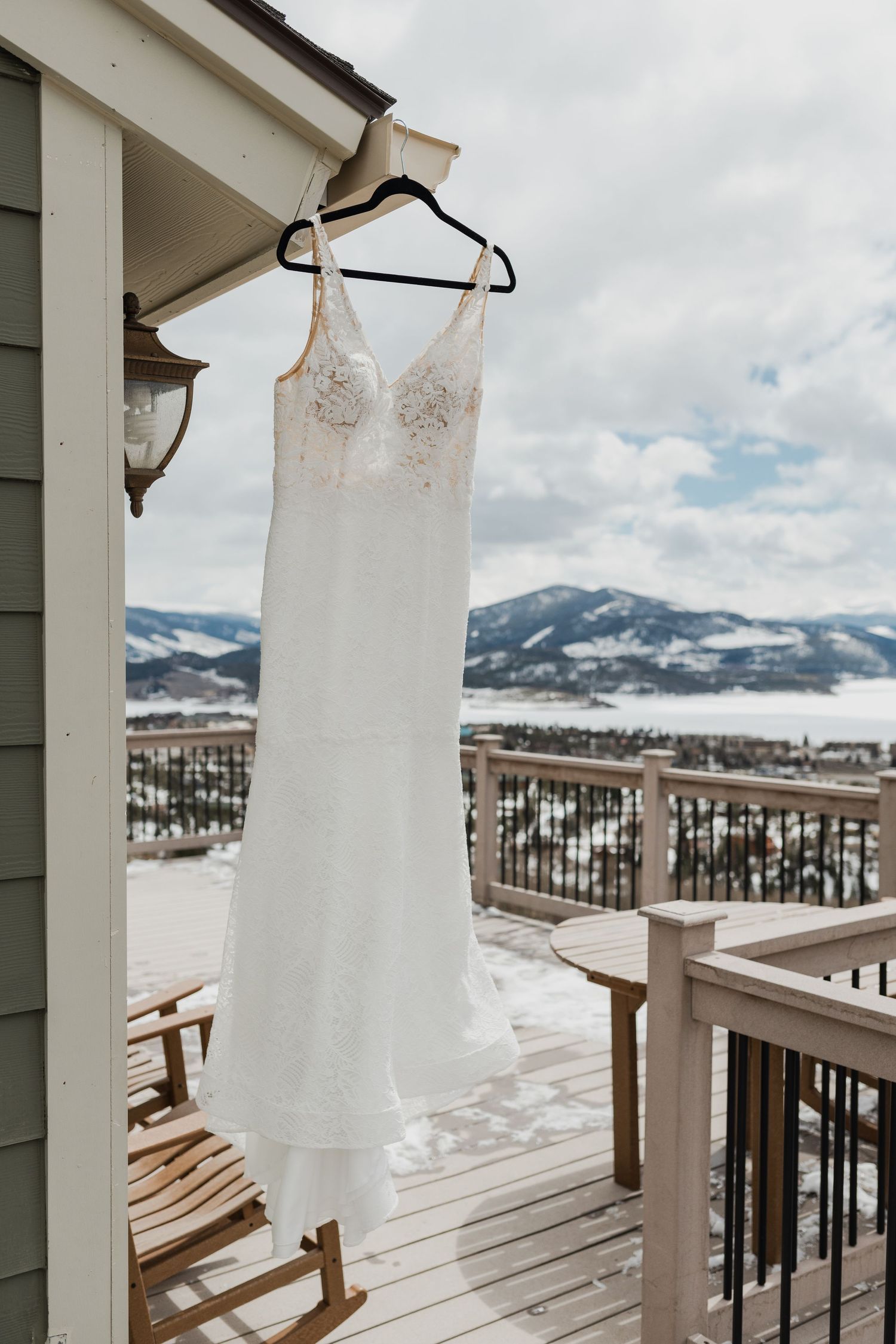 White wedding dress hanging on balcony with snowy mountain landscape in background.