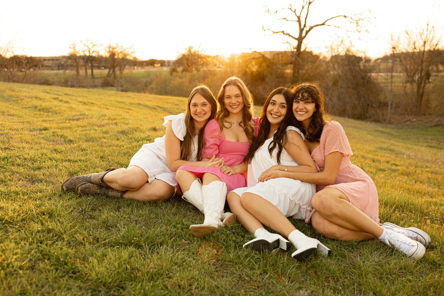 Friends relaxing on grass during outdoor golden hour photoshoot.