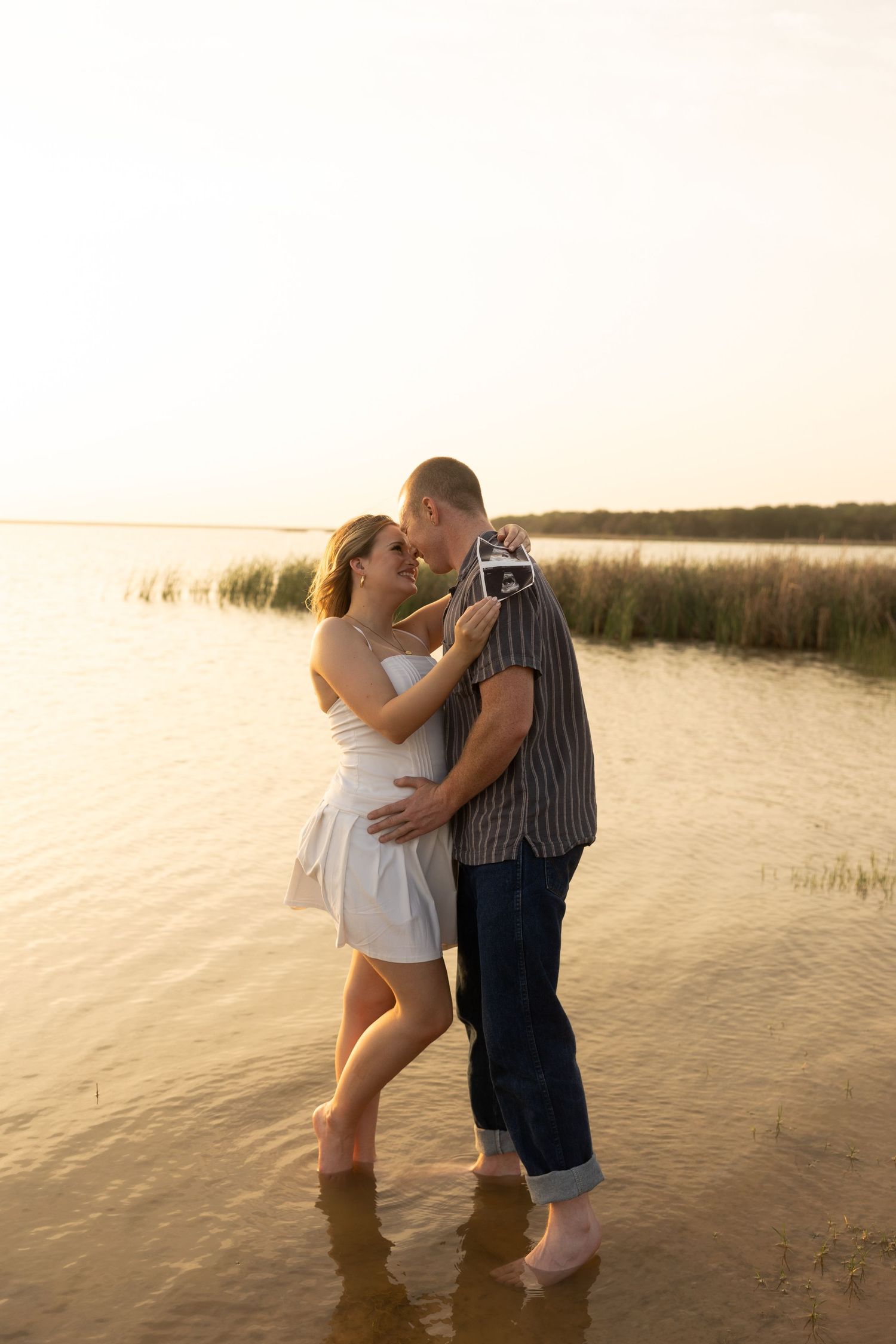 Couple sharing intimate moment in shallow water at sunset beach.