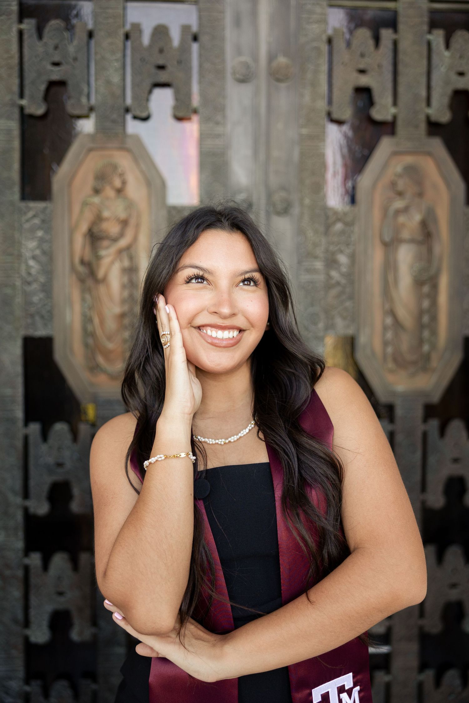 Graduation portrait with ornate architectural backdrop and maroon Texas A&M stole.