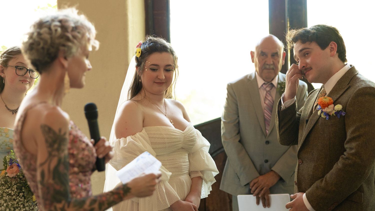 A group gathers for an emotional wedding ceremony moment indoors.