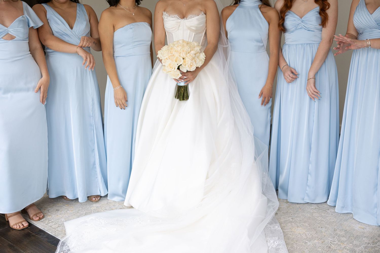 Row of bridesmaids in light blue dresses standing together at an outdoor wedding ceremony.